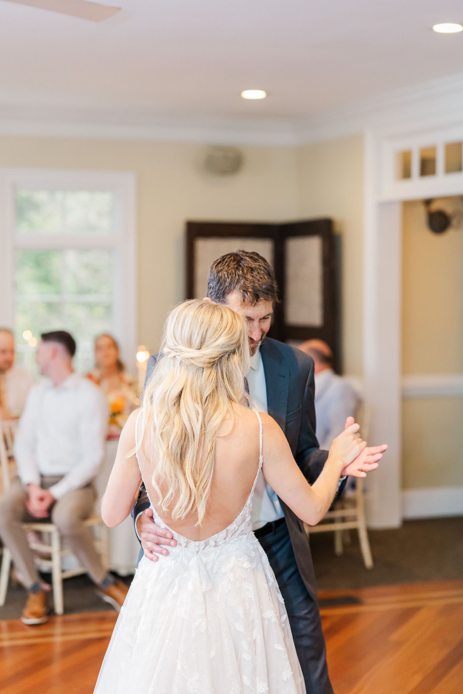 Newlyweds share their first dance on a polished hardwood floor at their wedding reception.