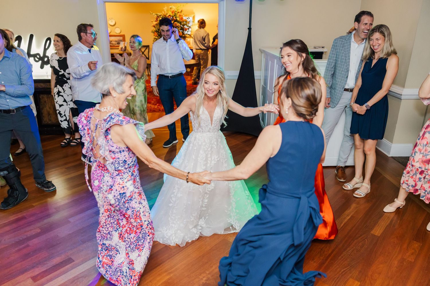 Wedding guests dance and celebrate on a wooden dance floor at a reception.