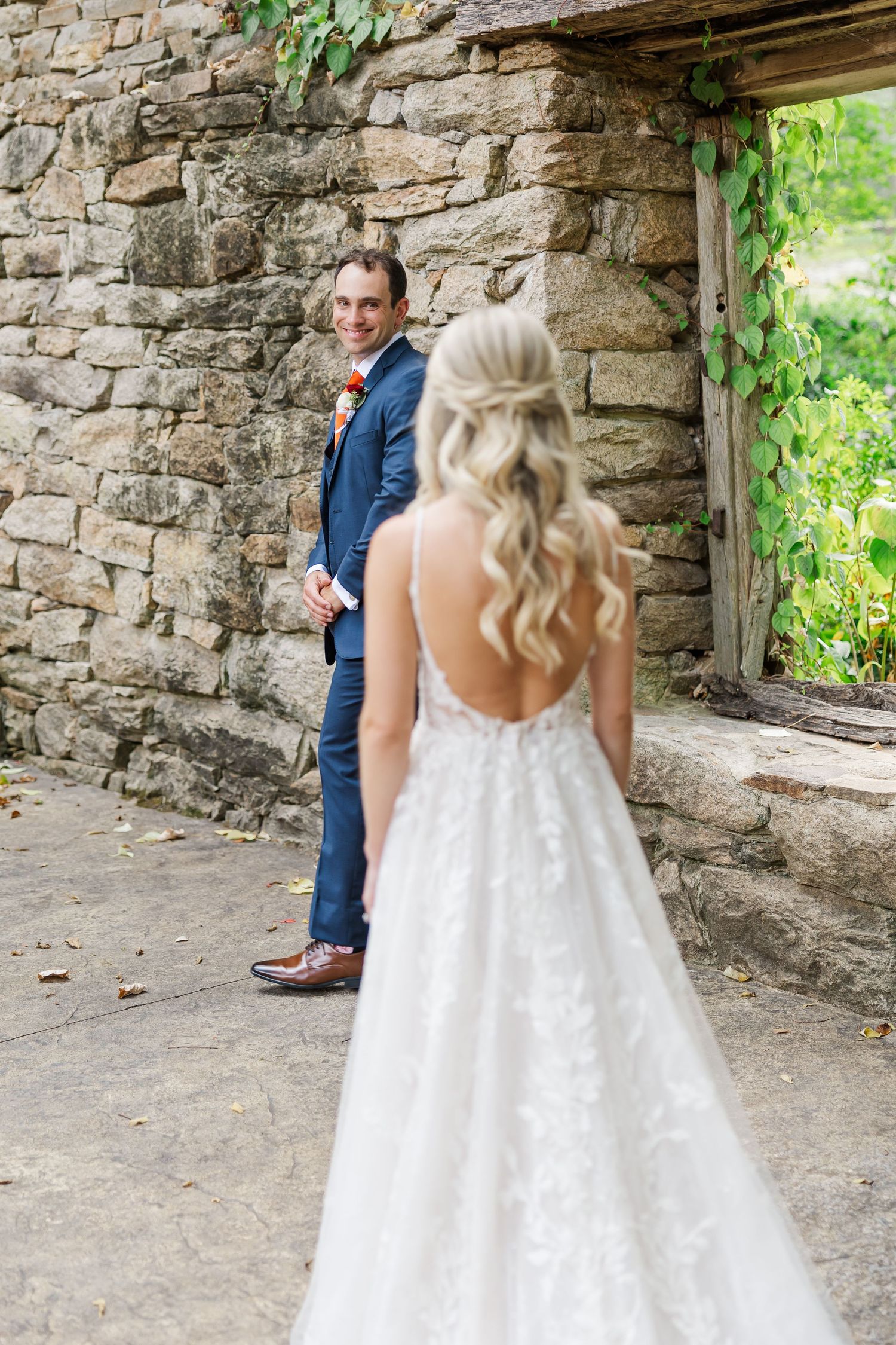 A couple shares a romantic first look moment in a rustic stone archway during their wedding day.