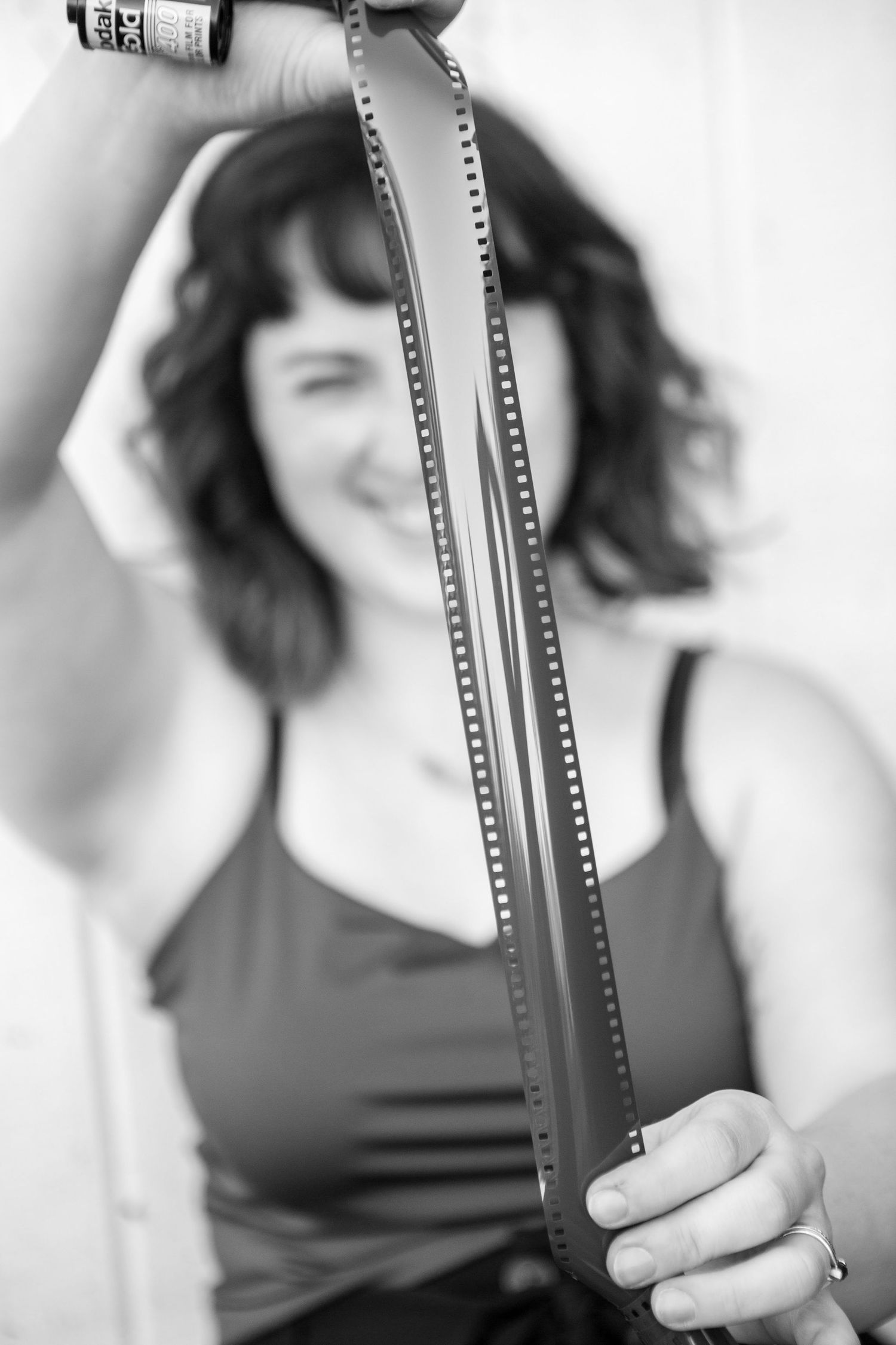 Black and white portrait of someone holding film strips.