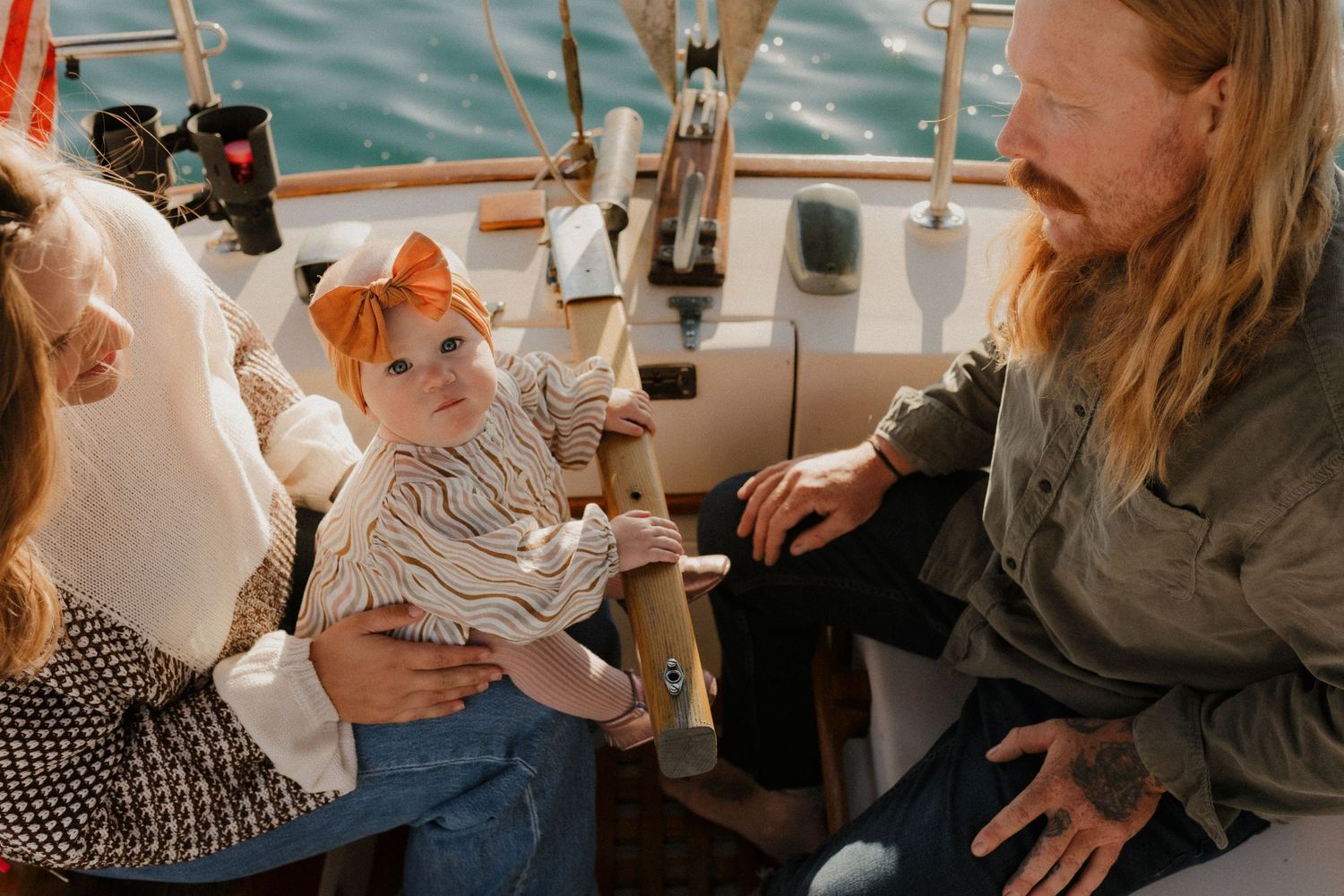 A family photography session as they sits on a boat with others during a sunny day on the water.