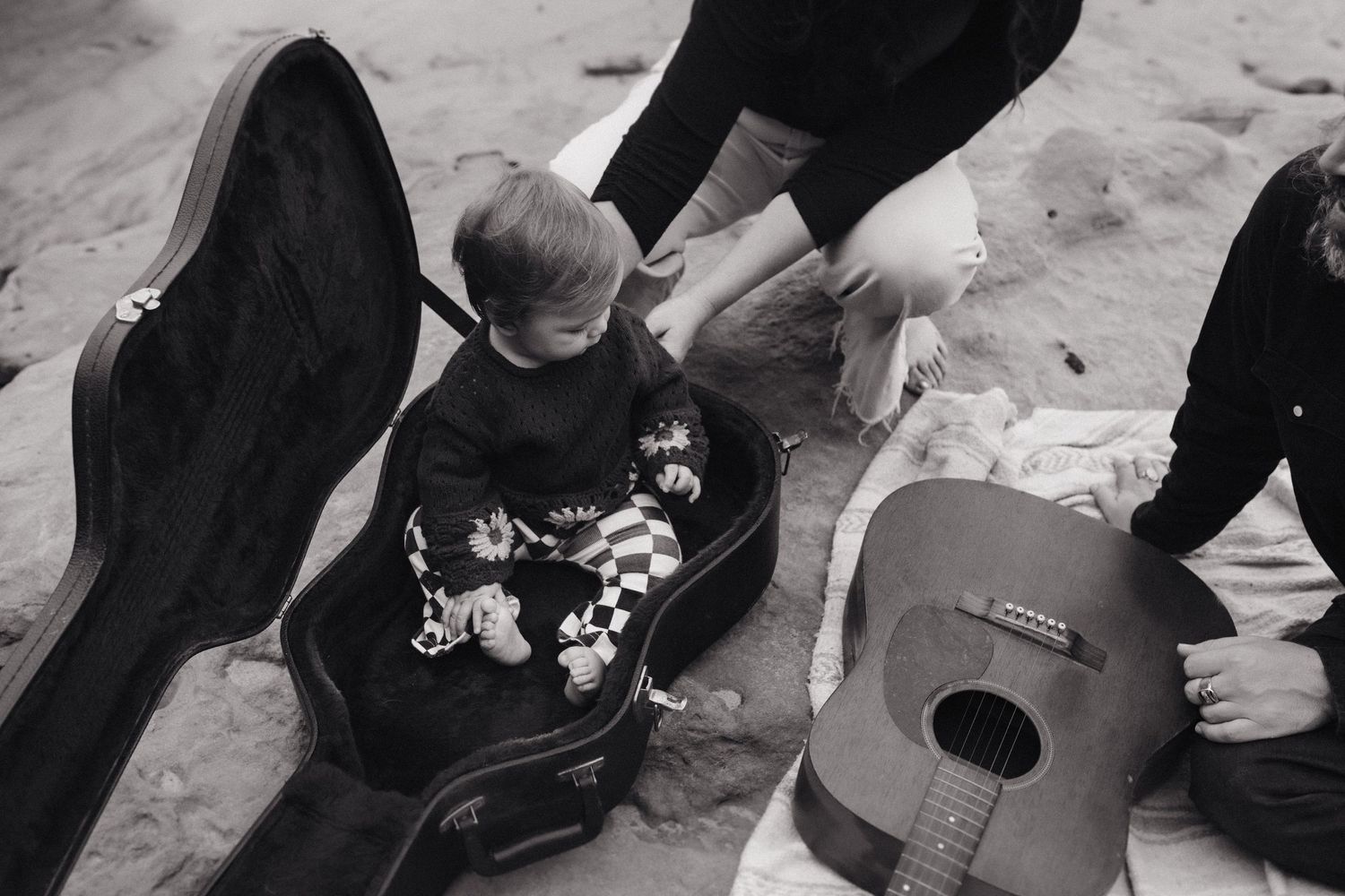 Black and white photo of guitar case and musical equipment on ground.