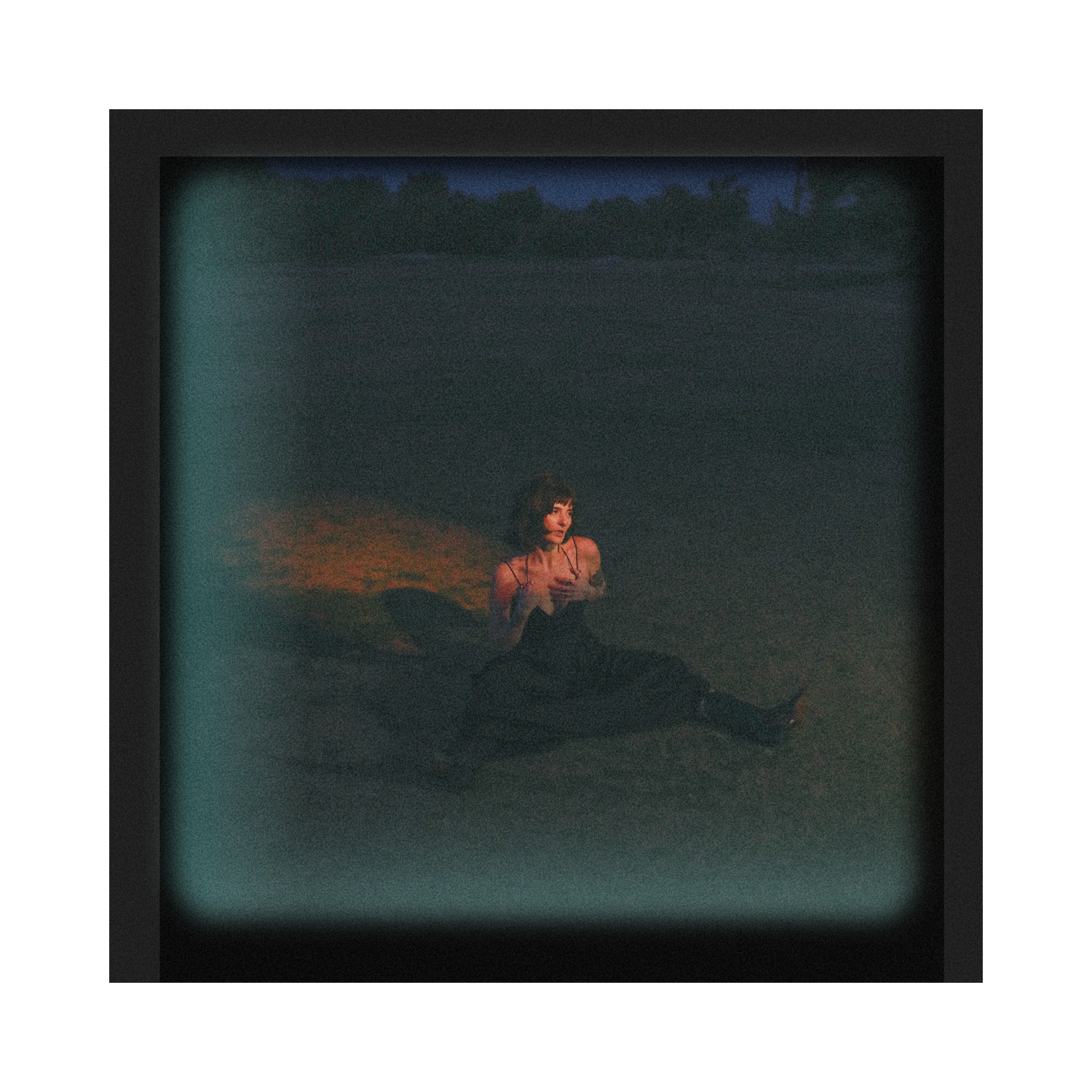 Moody vintage-style photograph of someone sitting alone outdoors at dusk.