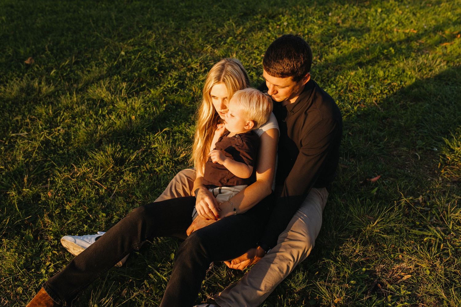 Intimate outdoor portrait in golden sunlight on grassy hill.