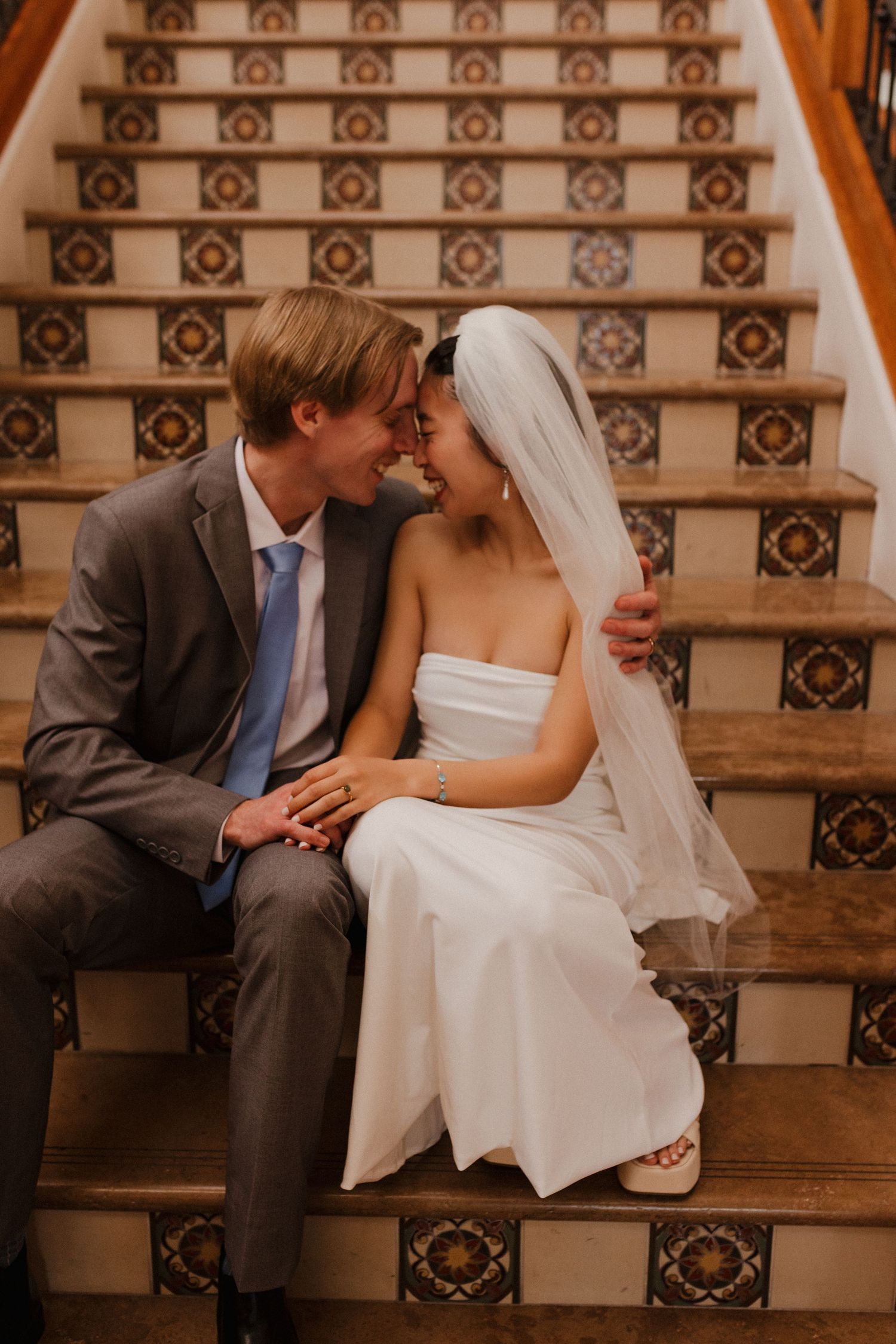 A bride and groom share an intimate moment on ornate tiled steps during their wedding celebration.