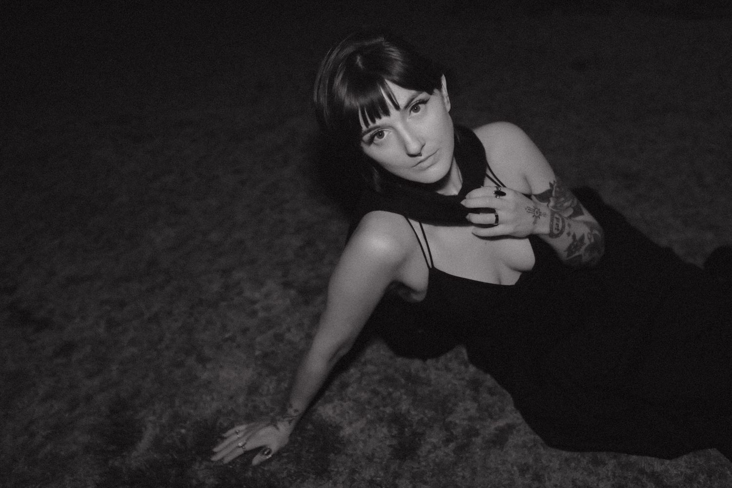 Dramatic black and white portrait of someone in dark clothing lying on the ground.