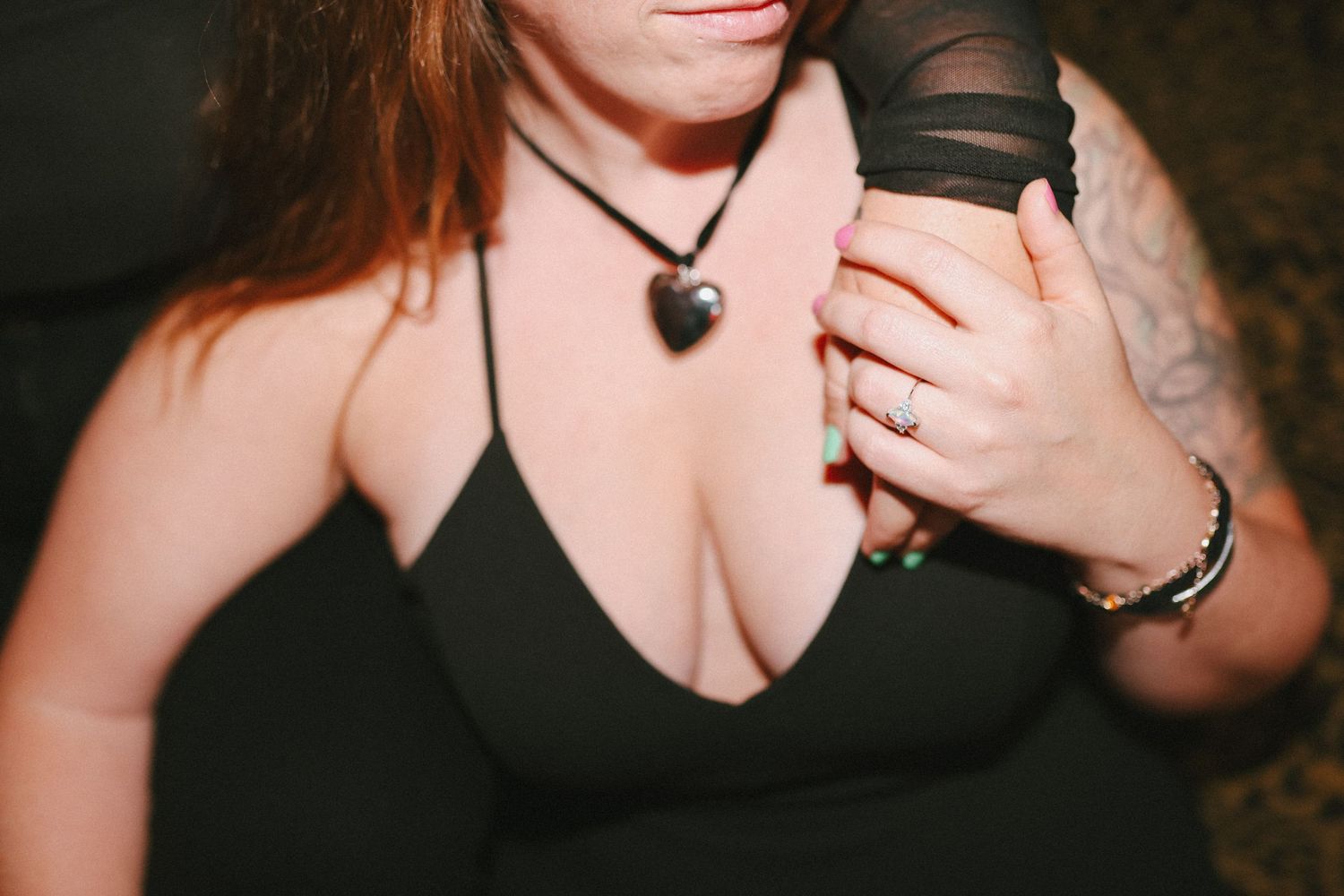 Close-up of jewelry and accessories on someone wearing a black dress.