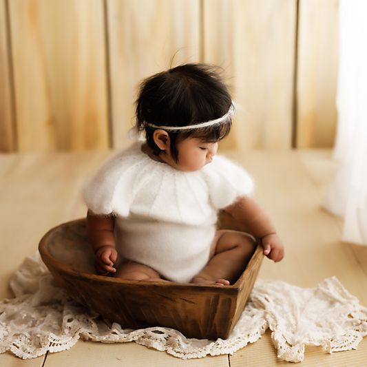A baby in a white dress crawls on the floor, with lace trim visible in a series of connected images.