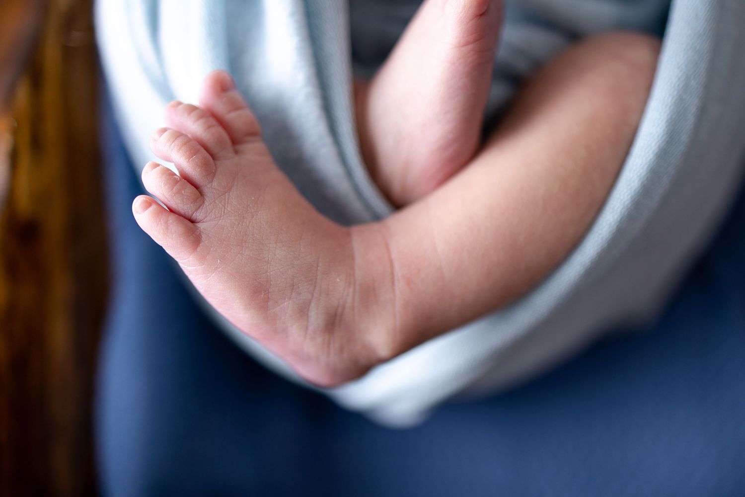 Close-up of tiny baby feet wrapped in light blue swaddle.