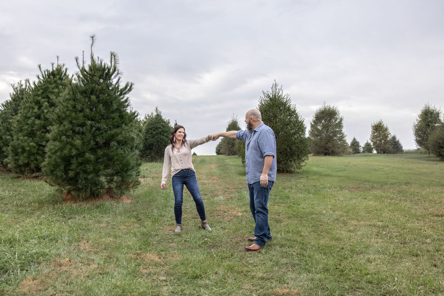 Couple walking together through a grassy outdoor field on a cloudy day.