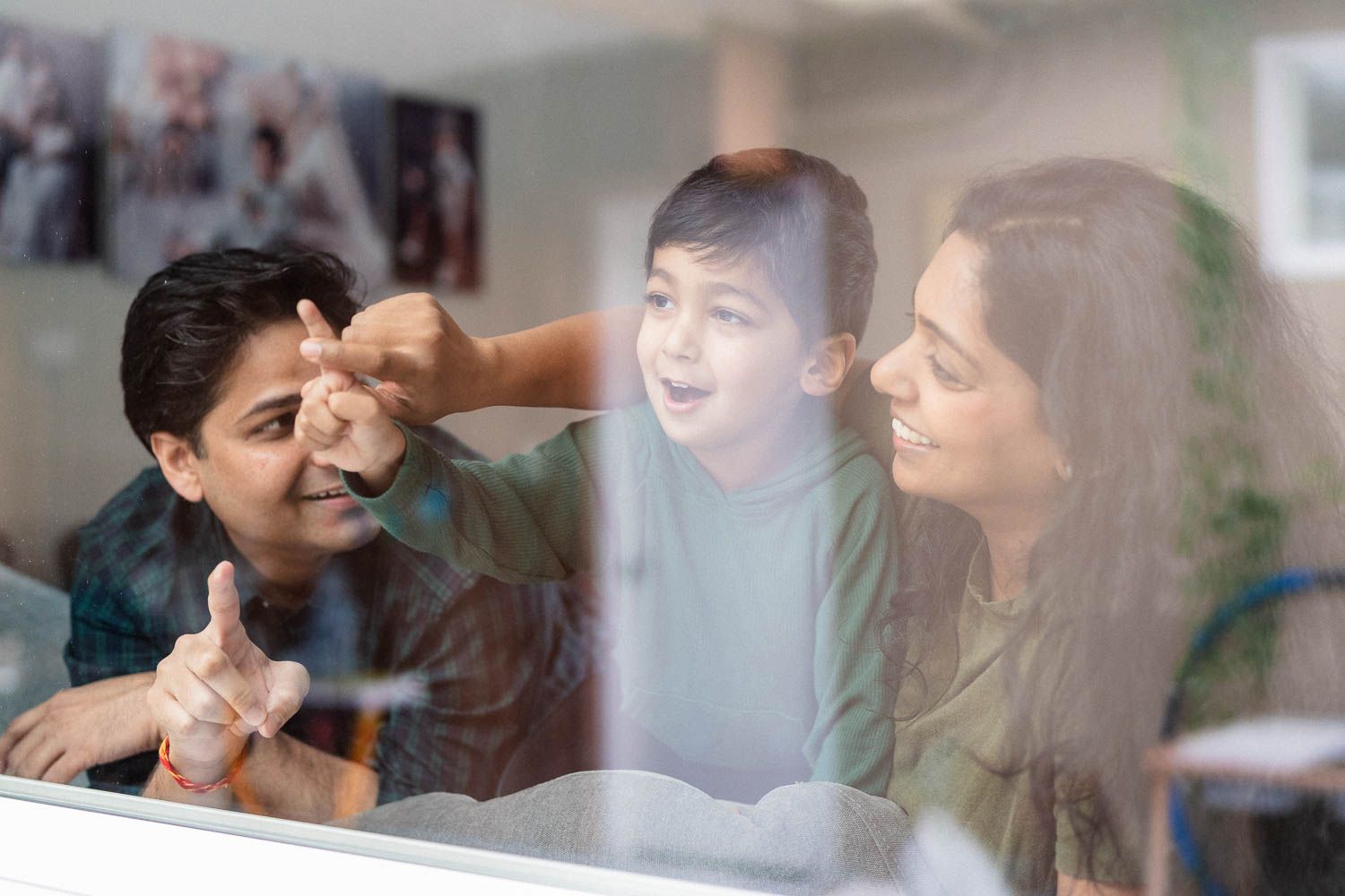 Family of three share an engaging conversation while cuddling together at the window, sharing warm smiles and laughter.