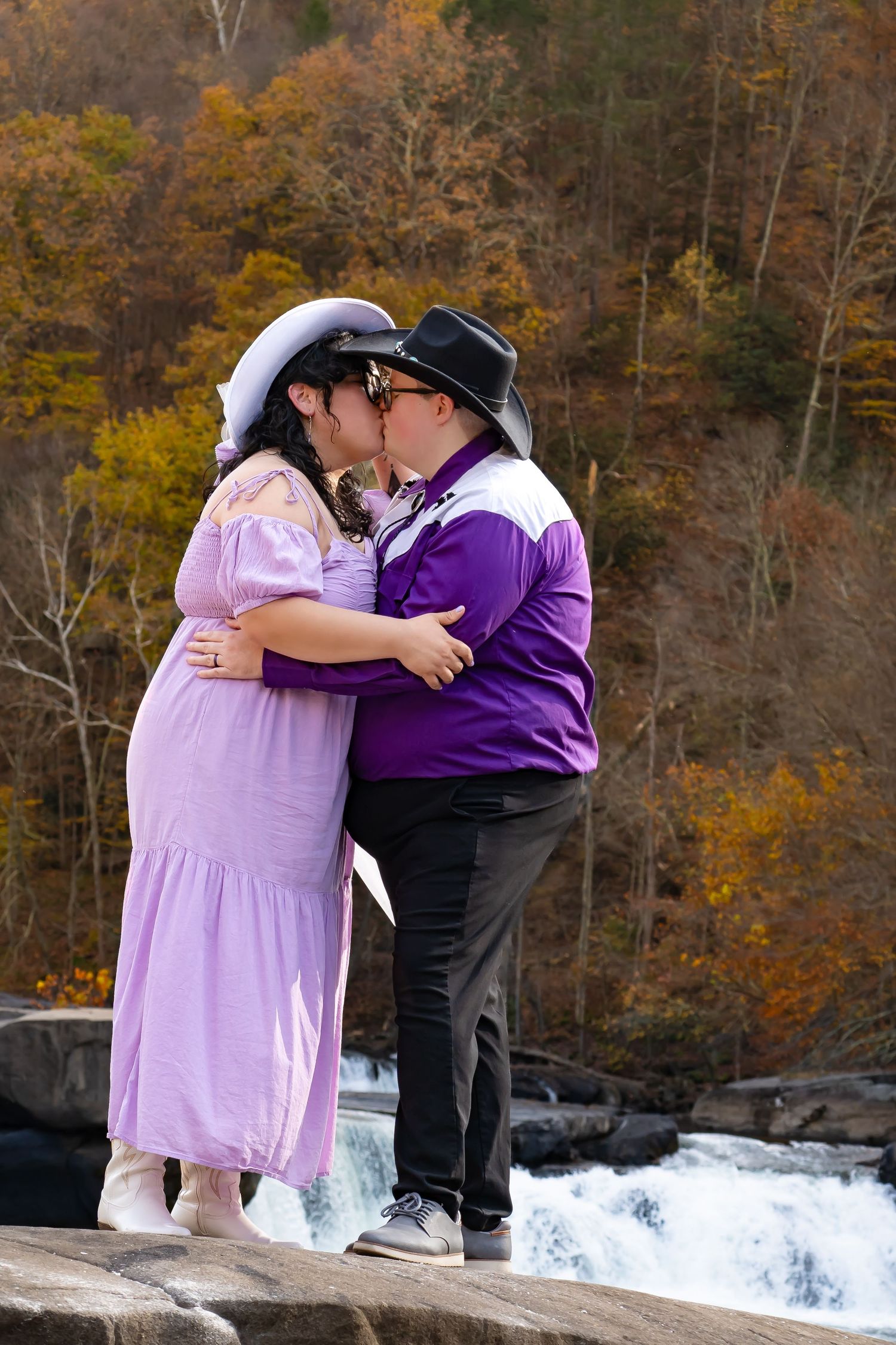 Couple shares a romantic moment at the edge of a waterfall surrounded by autumn foliage. Valley falls, Fairmont West Virginia