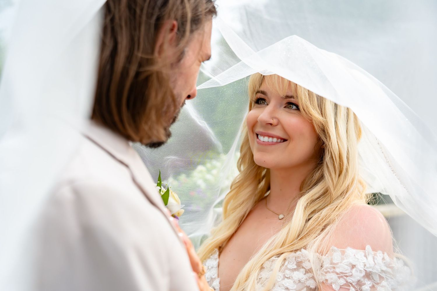 A couple shares a romantic moment under a white veil during their outdoor wedding photoshoot. Marengo, Ohio , the brook