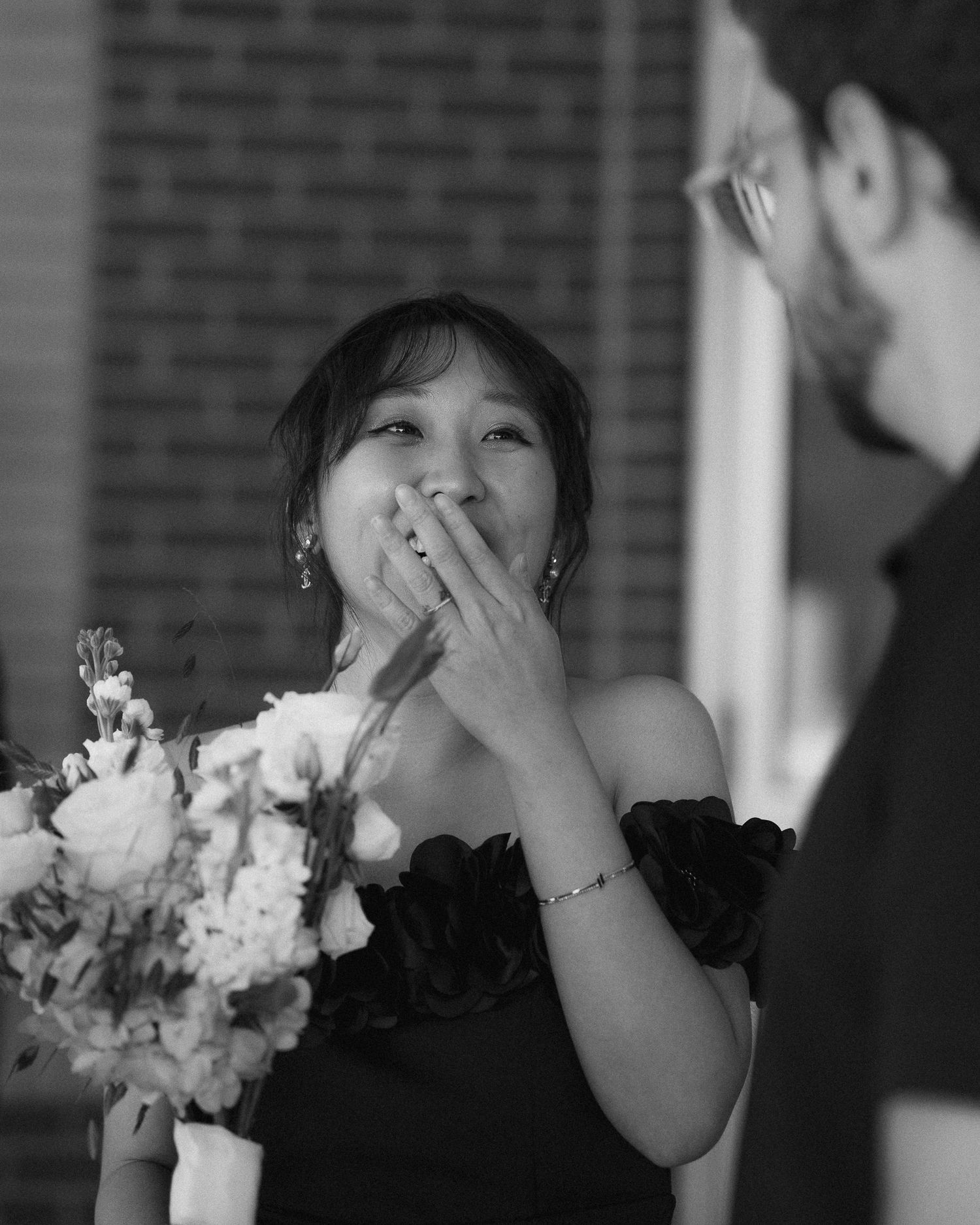 Black and white sequence showing emotional reaction to surprise proposal with white bouquet.
