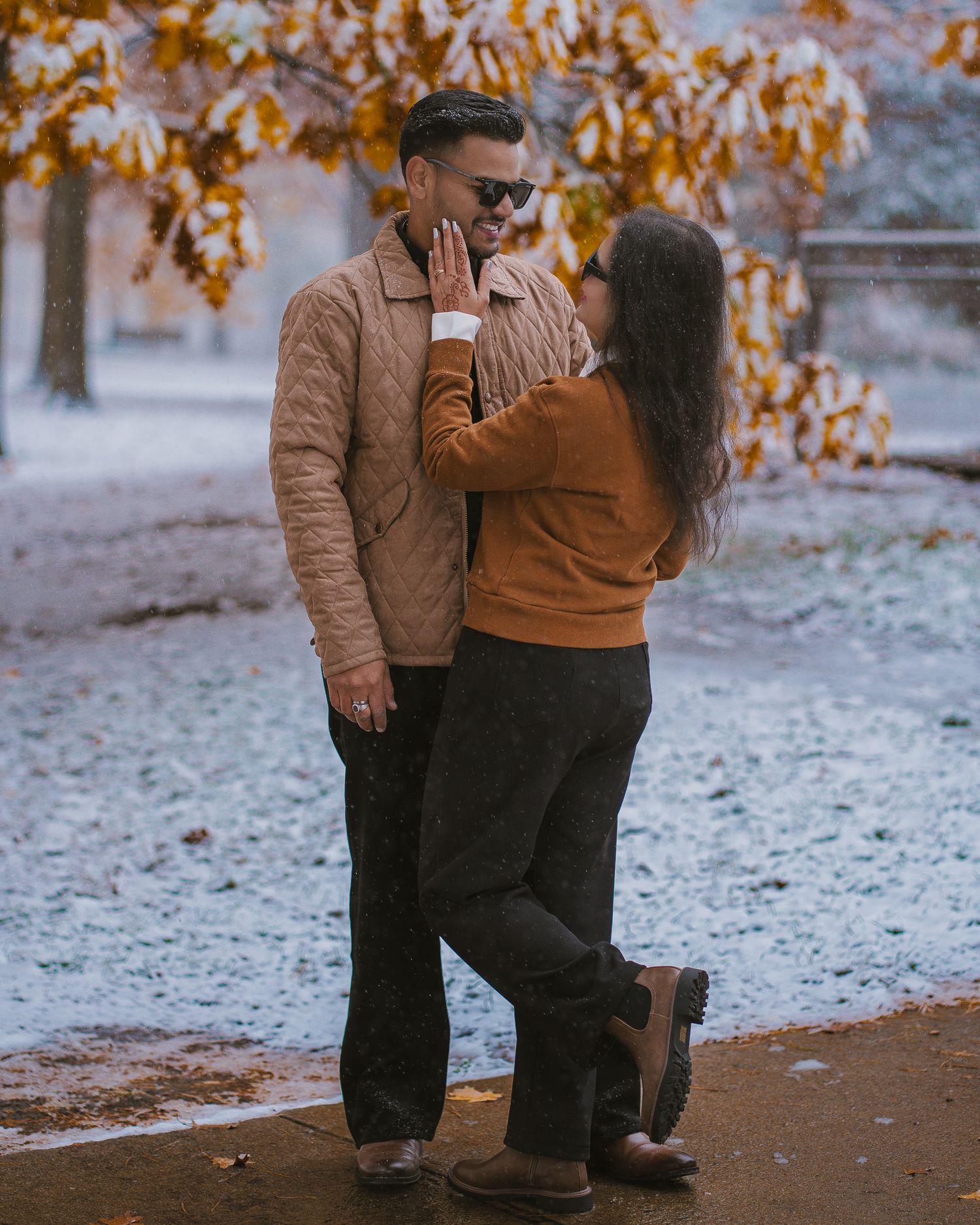 Romantic autumn scene with couple embracing in light snow covered landscape.