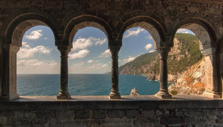 Stone arched colonnade overlooking the stunning Ligurian Sea coastline and rocky cliffs in Portovenere, Italy.
