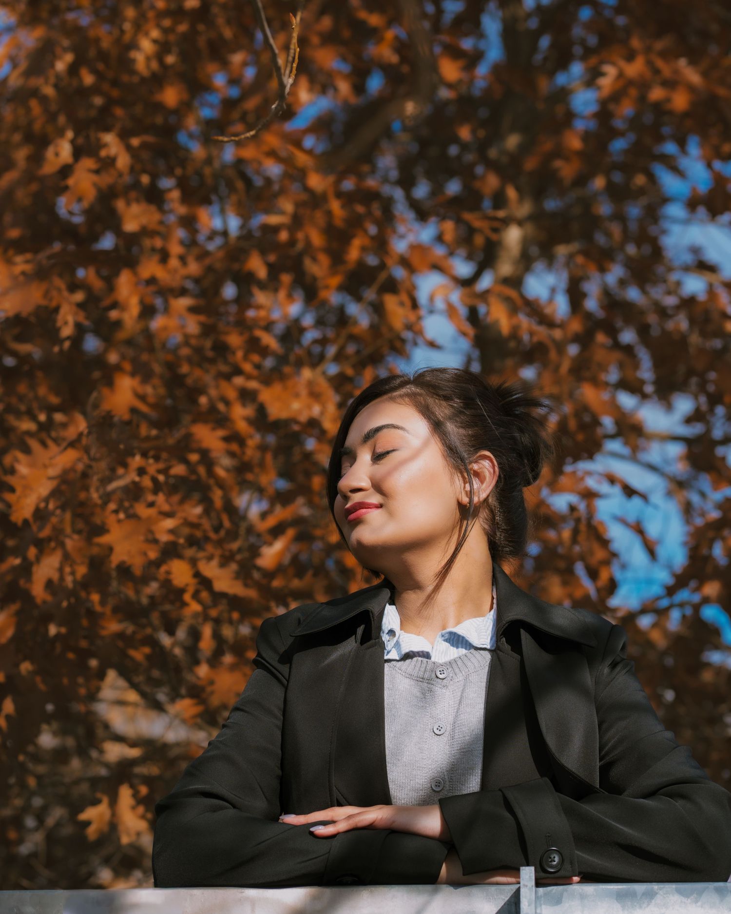 Portrait against autumn foliage with orange leaves and blue sky background.