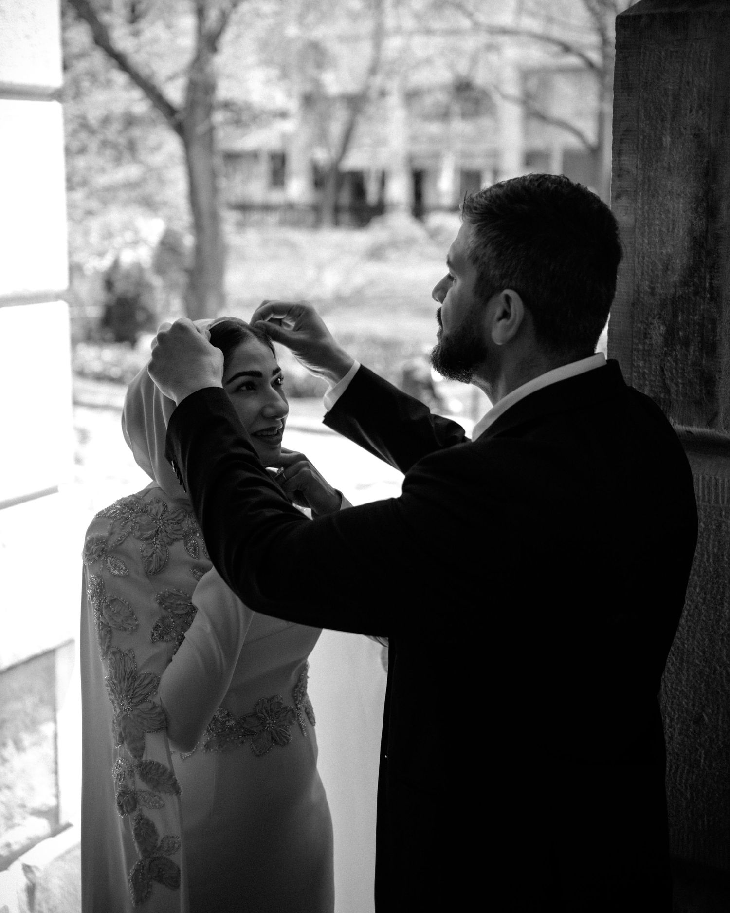 Black and white photo of a groom adjusting his brides veil on their wedding day.