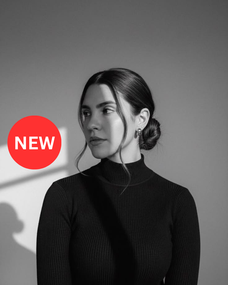 Black and white portrait of a woman in a black turtleneck sweater with hair in a bun, wearing earrings.