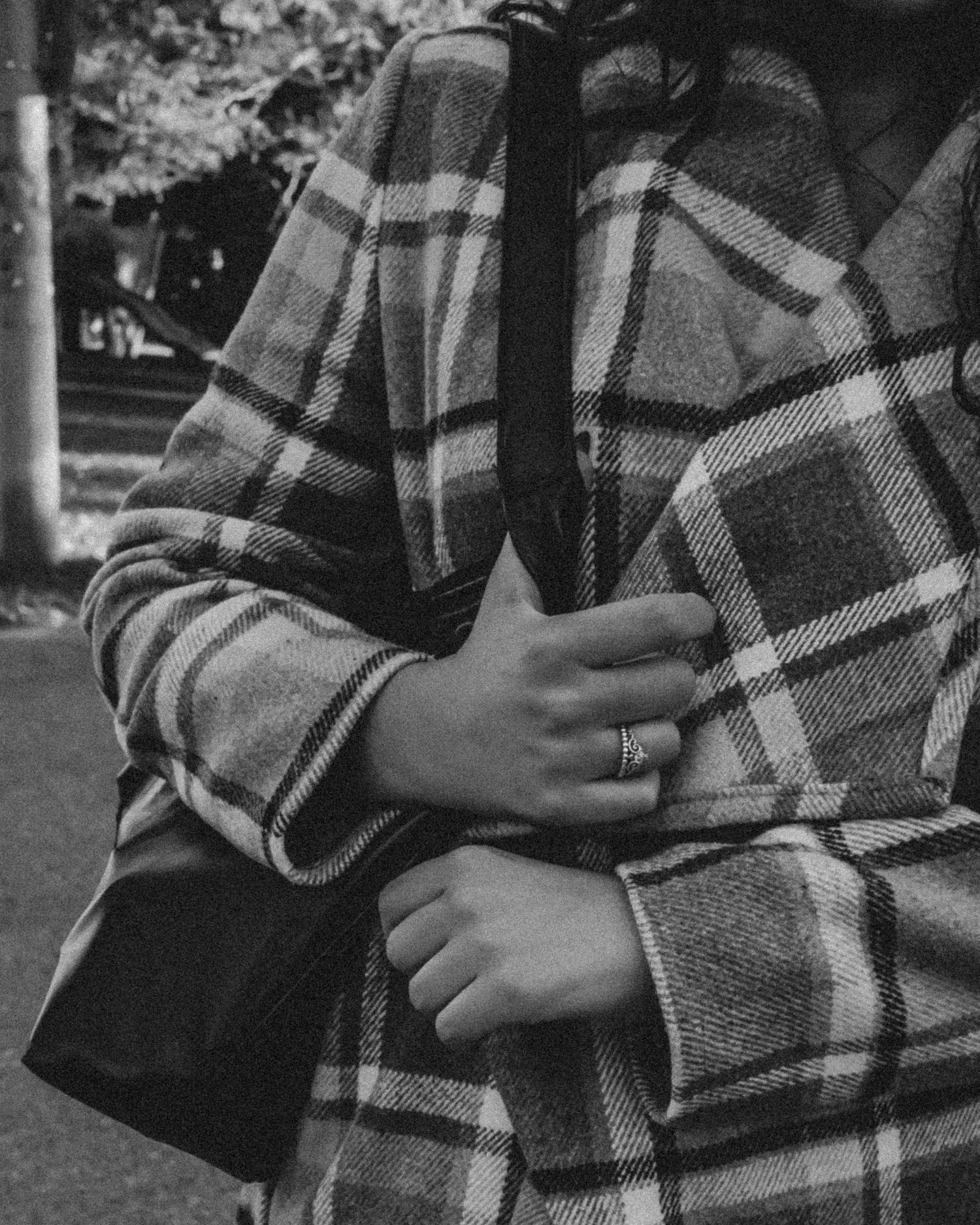 Close-up of plaid flannel jacket with wedding ring detail in black and white.