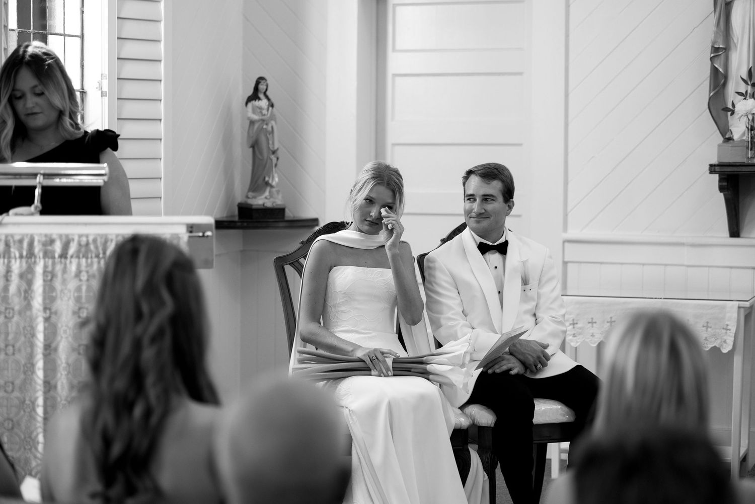 Bride in candid moment wiping a tear during wedding ceremony at St Marys Catholic Church Johns Island South Carolina