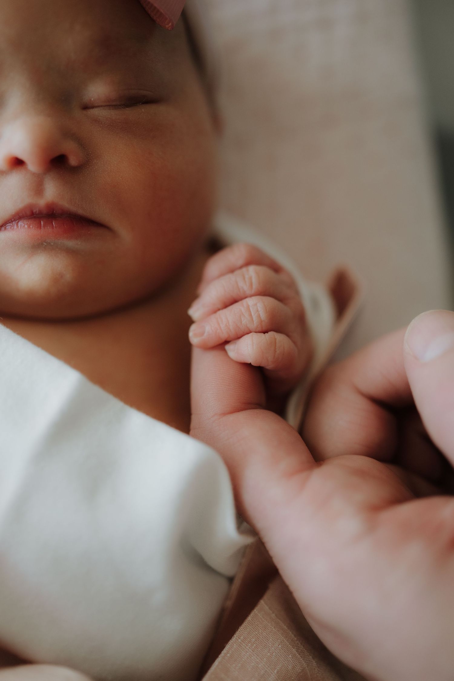 Close-up of a sleeping newborn's face and tiny hand.