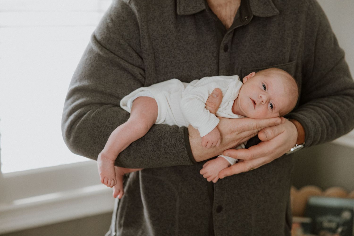 Lifestyle newborn photography session showing tender moments between parents and baby in natural window light.