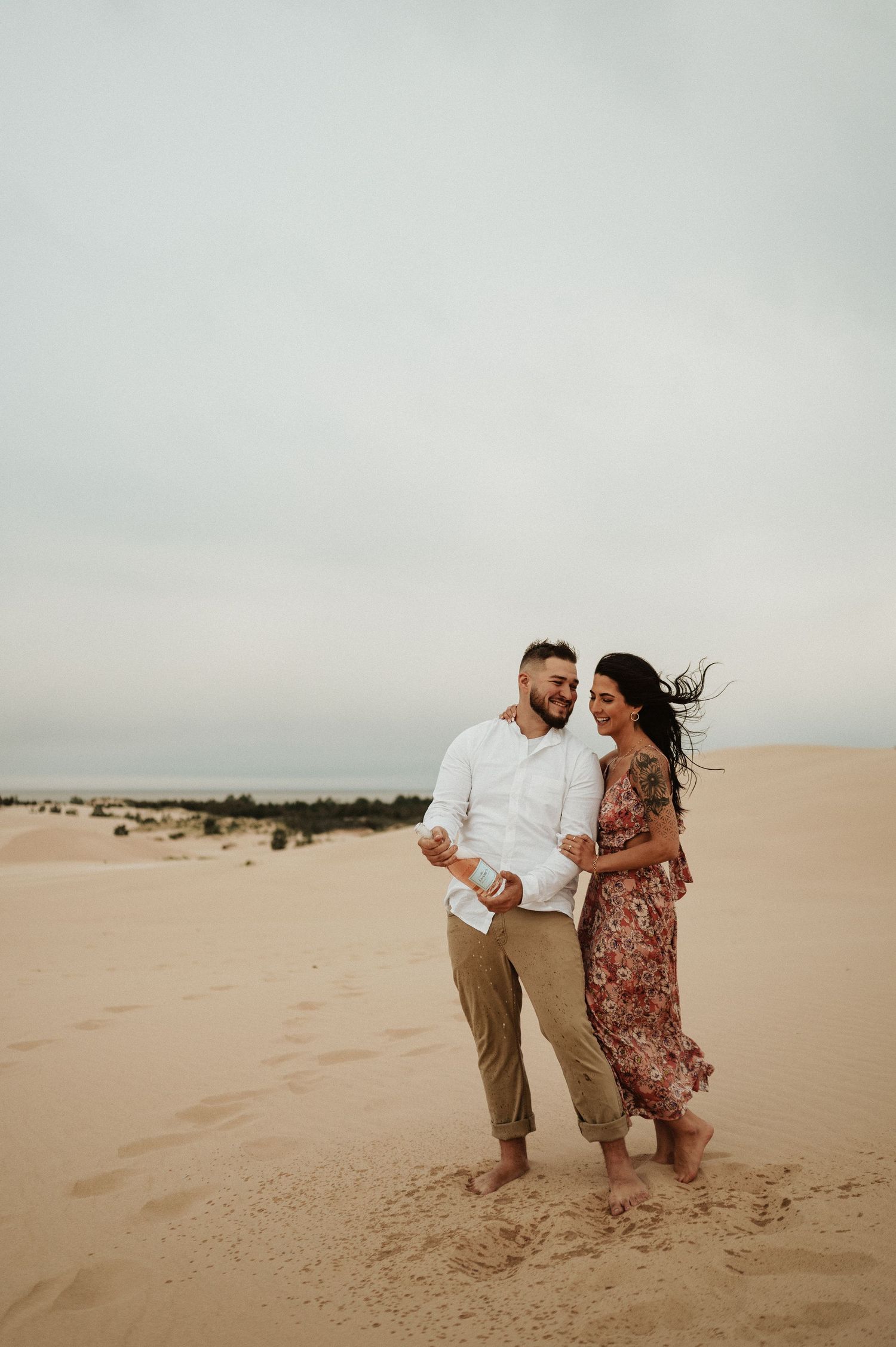 A couple stands close together on sandy dunes during an intimate desert photoshoot.