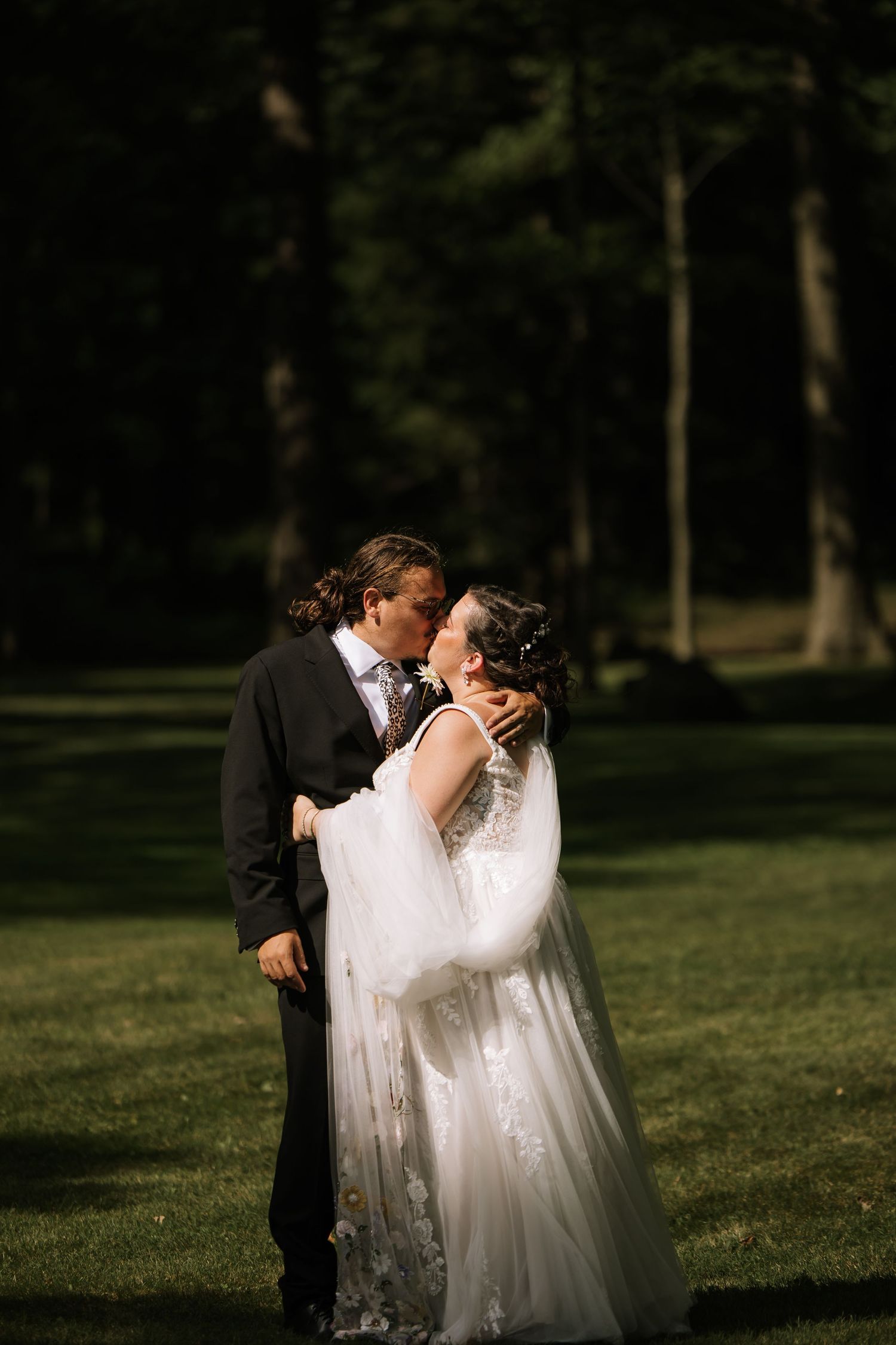 Romantic wedding couple sharing an intimate moment in a sunlit garden setting.