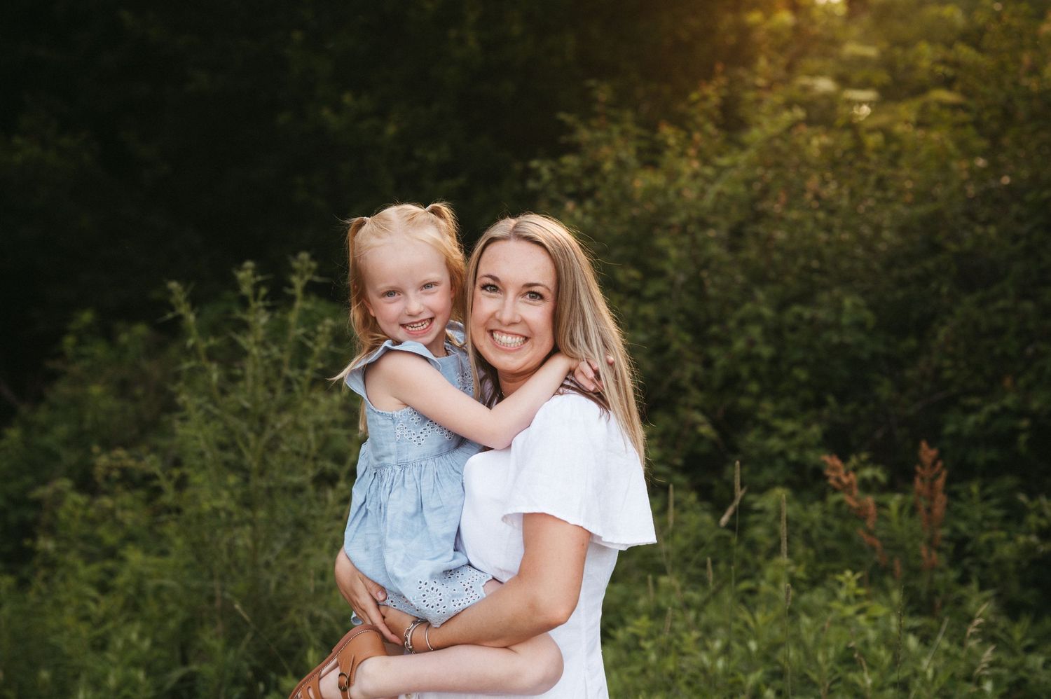 A sweet outdoor portrait of two people embracing against a natural green background.