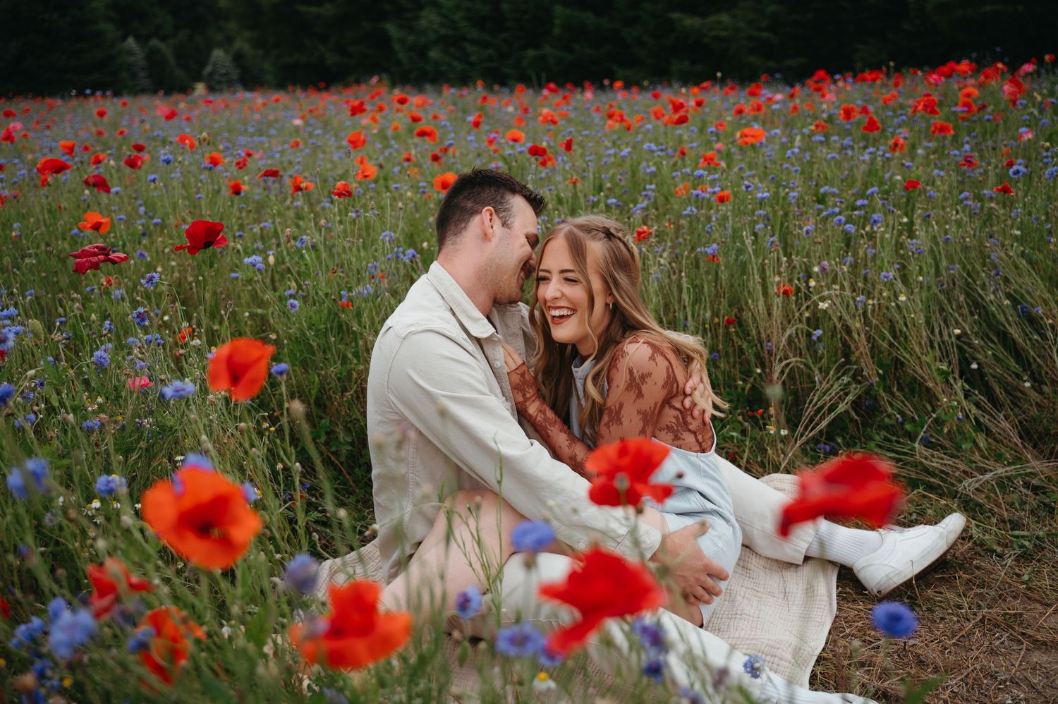 Loving embrace photographed in a summer field of red poppies and wildflowers.
