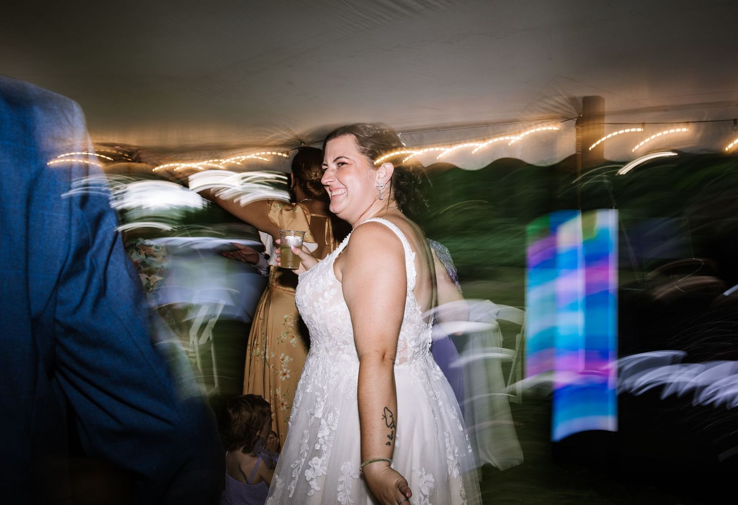 Motion-blurred dance floor scene with colorful lights at an evening wedding reception.