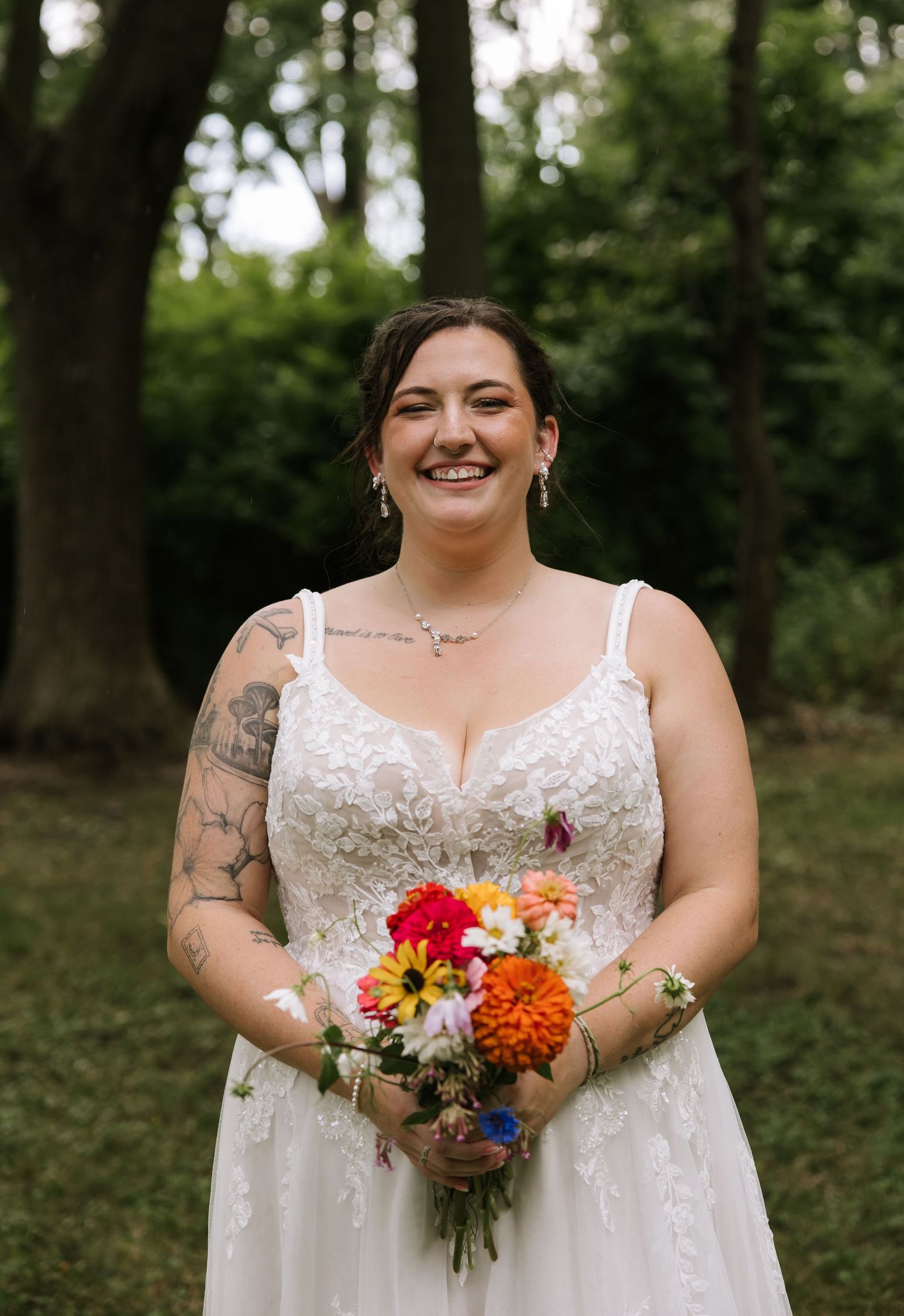 Wedding party in a wooded setting holding vibrant floral bouquets with white dresses.
