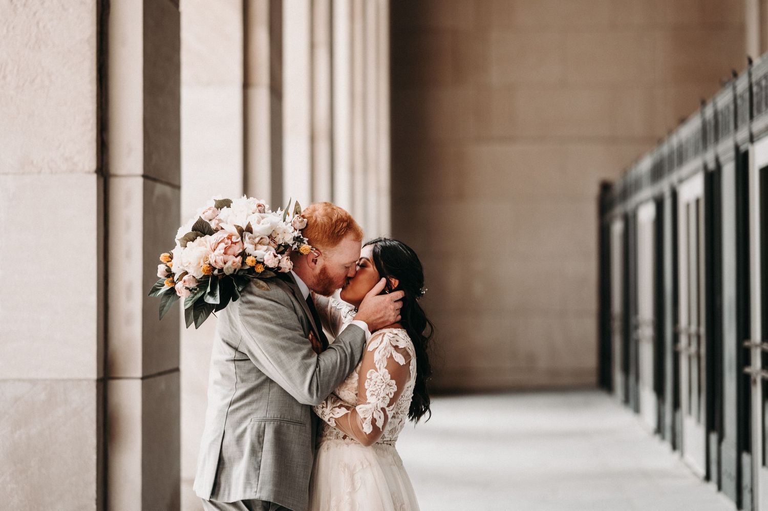 An intimate wedding portrait showing a tender moment between newlyweds in an elegant colonnade.