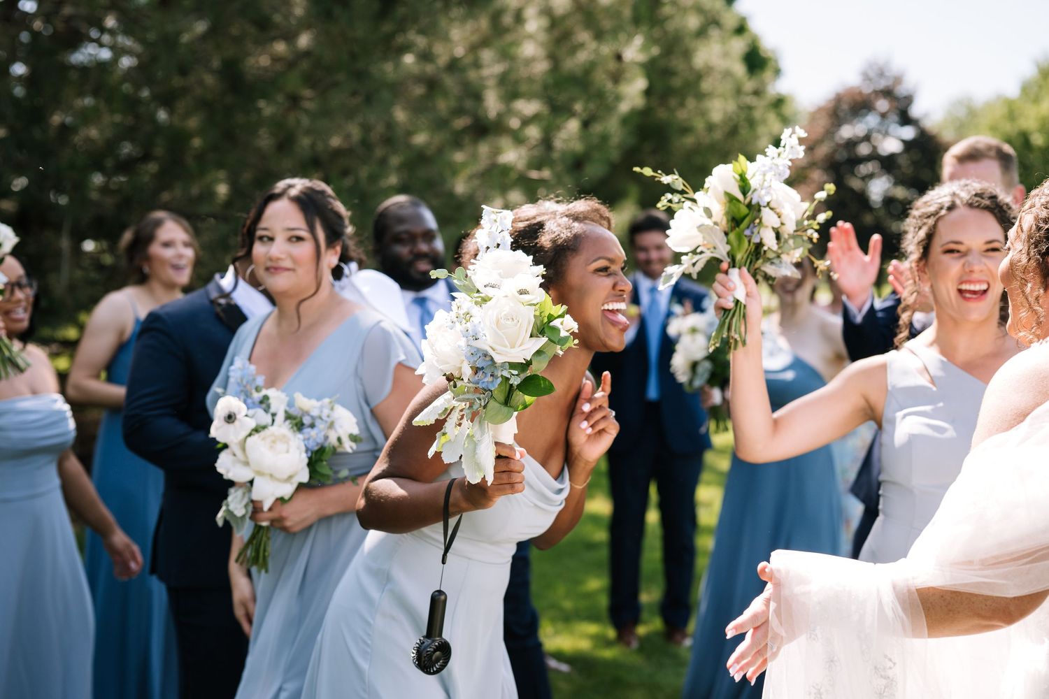 Joyful wedding guests and newlyweds celebrate with champagne toasts during an outdoor garden reception.