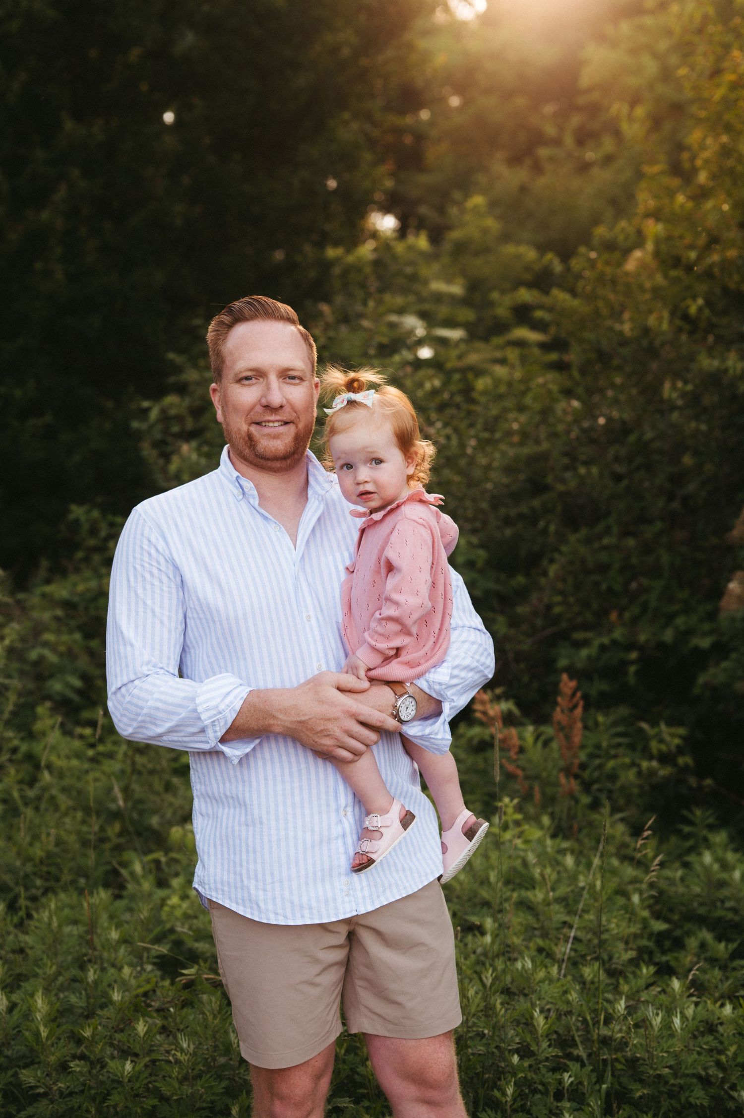 Parent and toddler in coordinated outfits share a joyful moment together outdoors during golden hour.