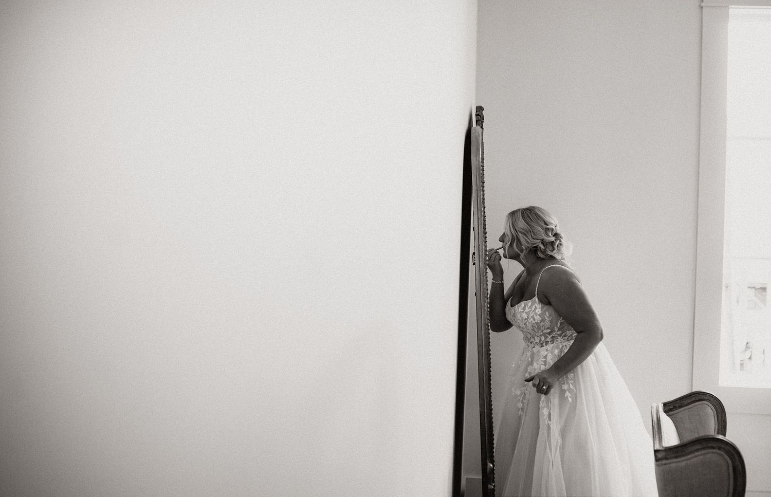 Black and white photo of someone in a wedding dress looking in a mirror.