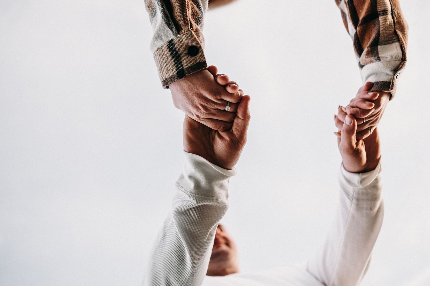 Close-up shot of two hands tenderly clasped together against a white background.