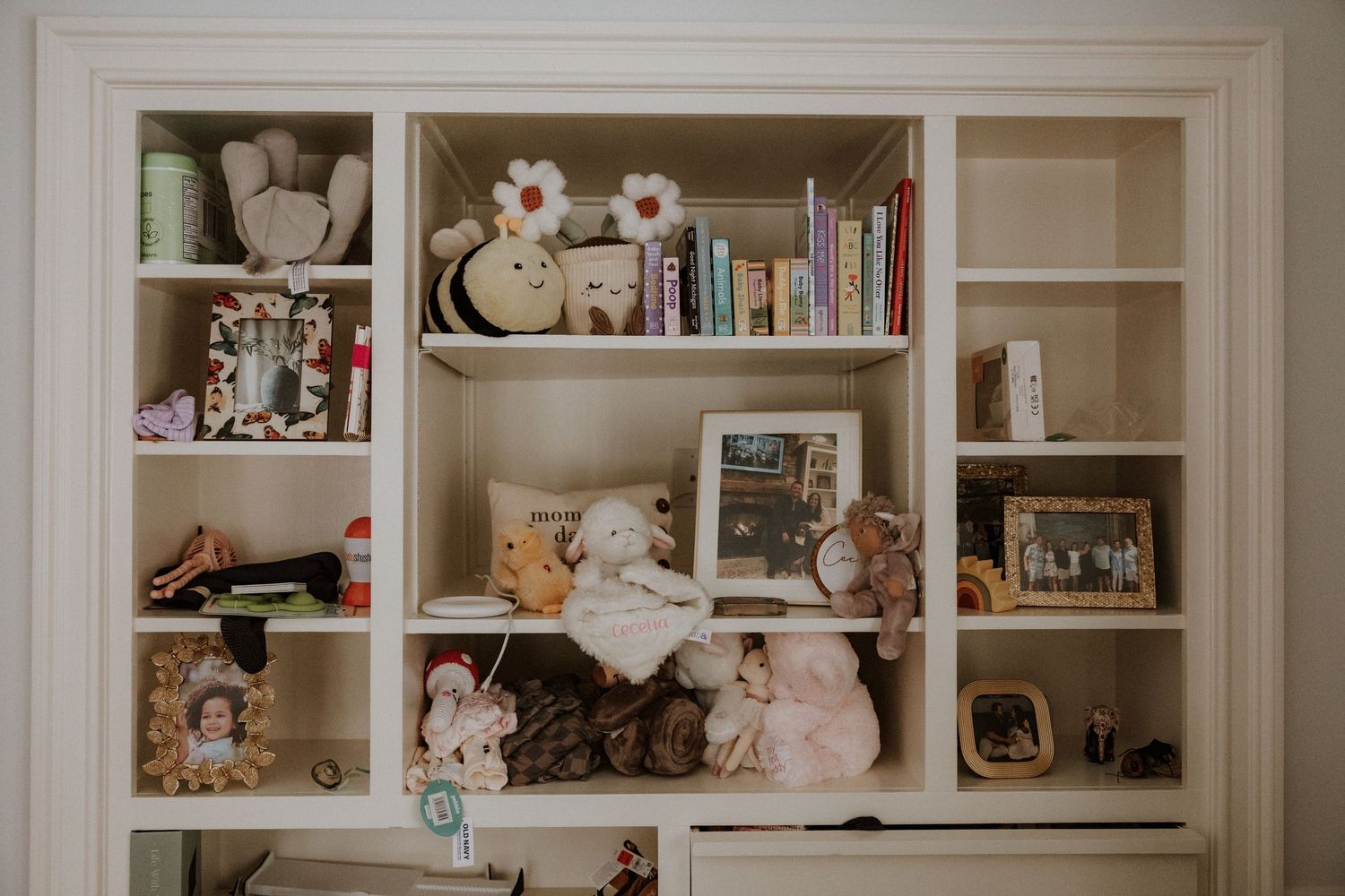 White built-in shelving unit displaying various collectibles, books, and decorative items in a home setting.