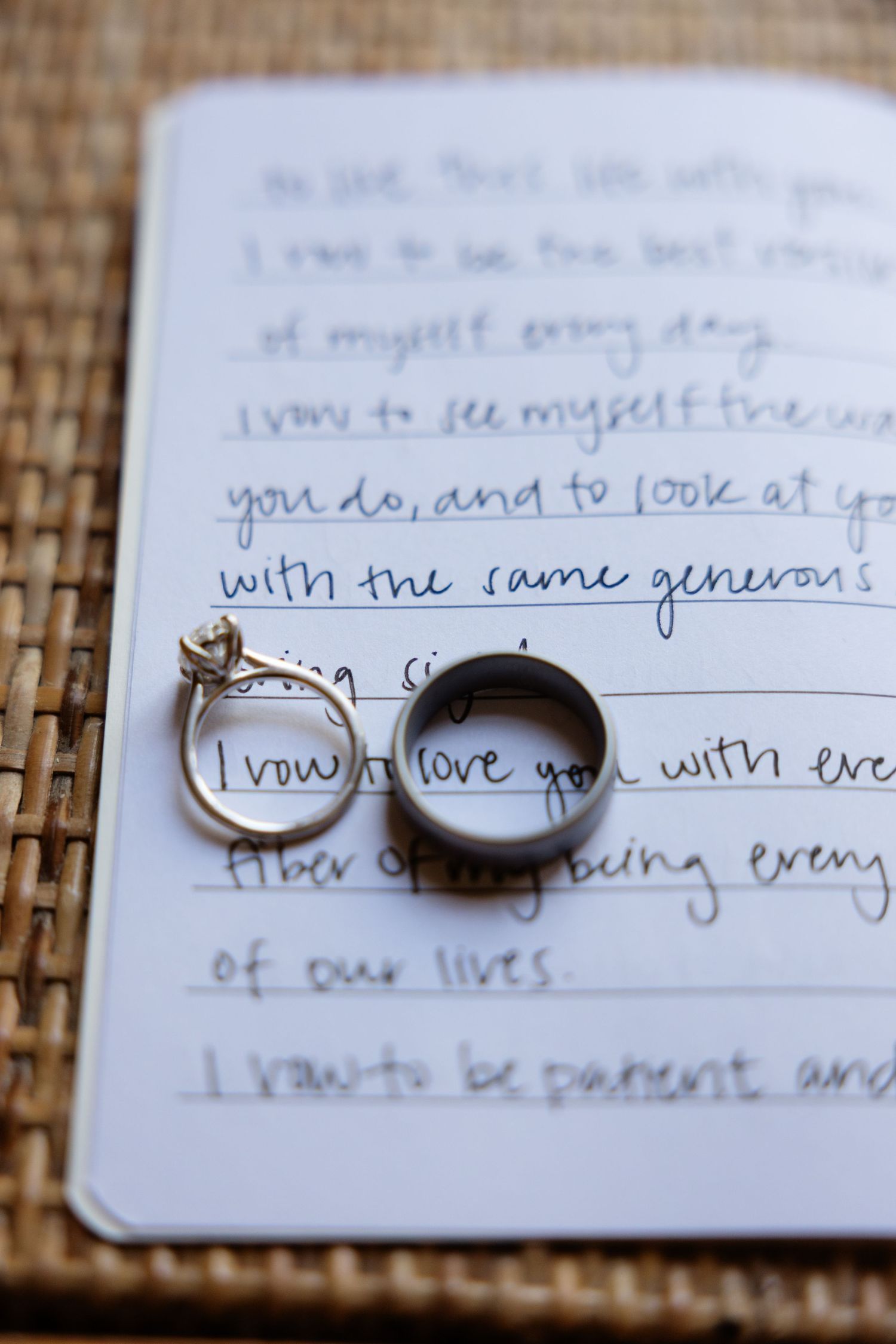 Wedding rings photographed on handwritten vows against a textured background.