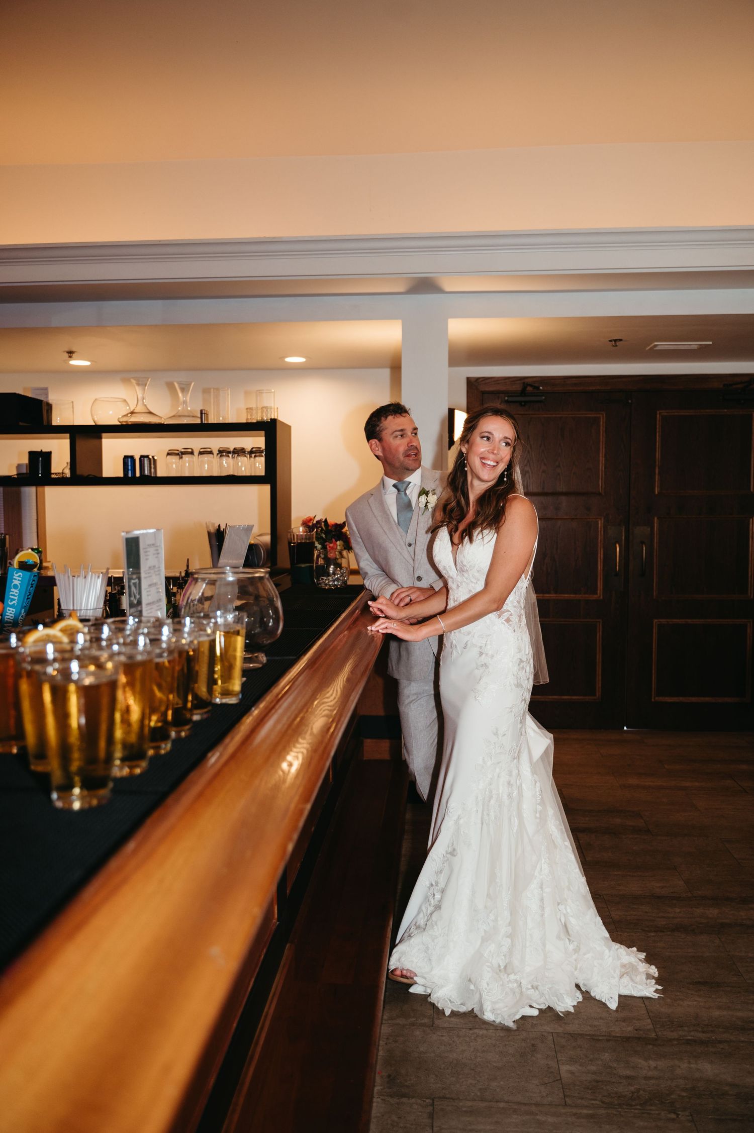 Wedding couple dancing together in an indoor venue with a long wooden bar counter visible.