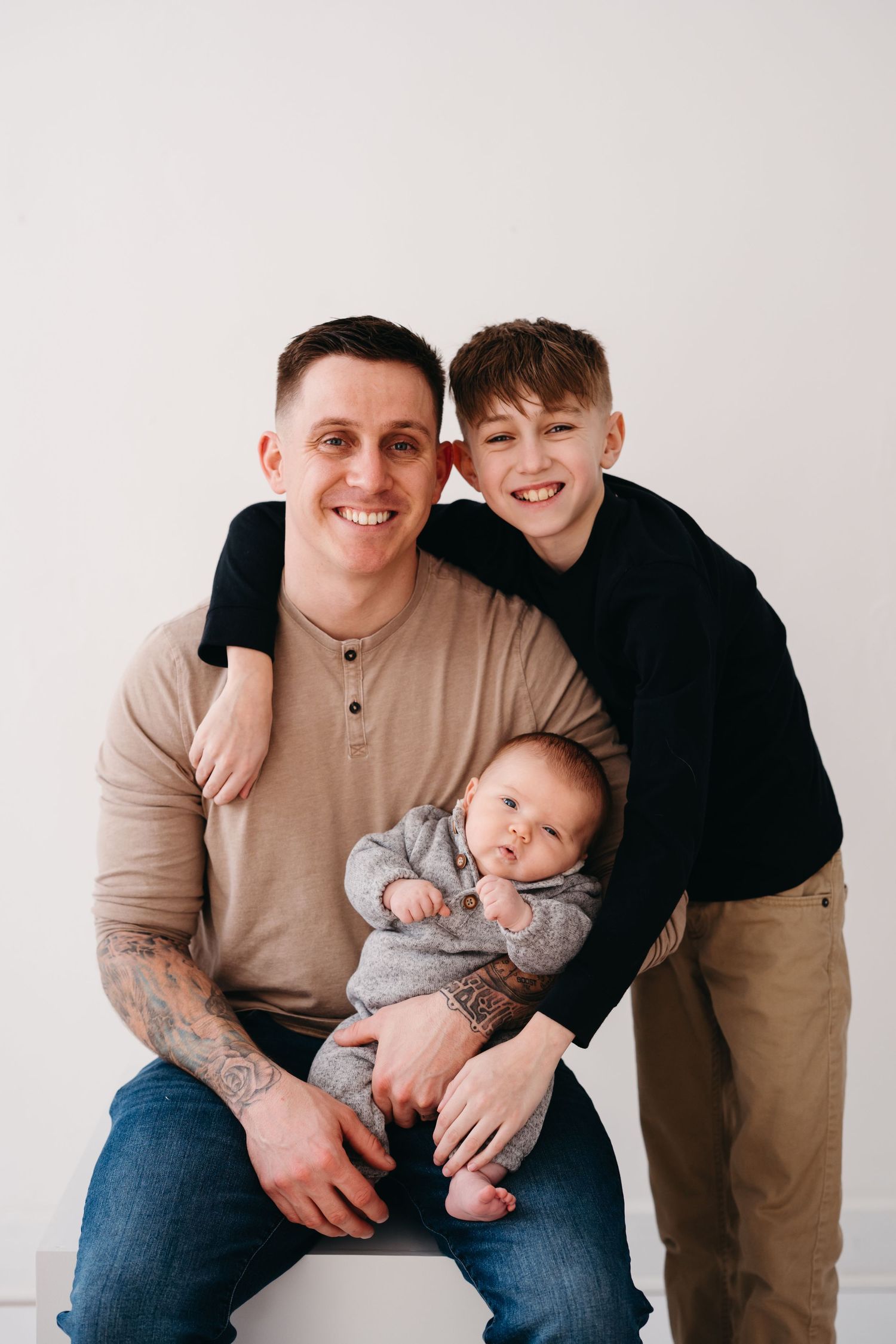 A warm family portrait showing tender moments between parent and children against a neutral background.