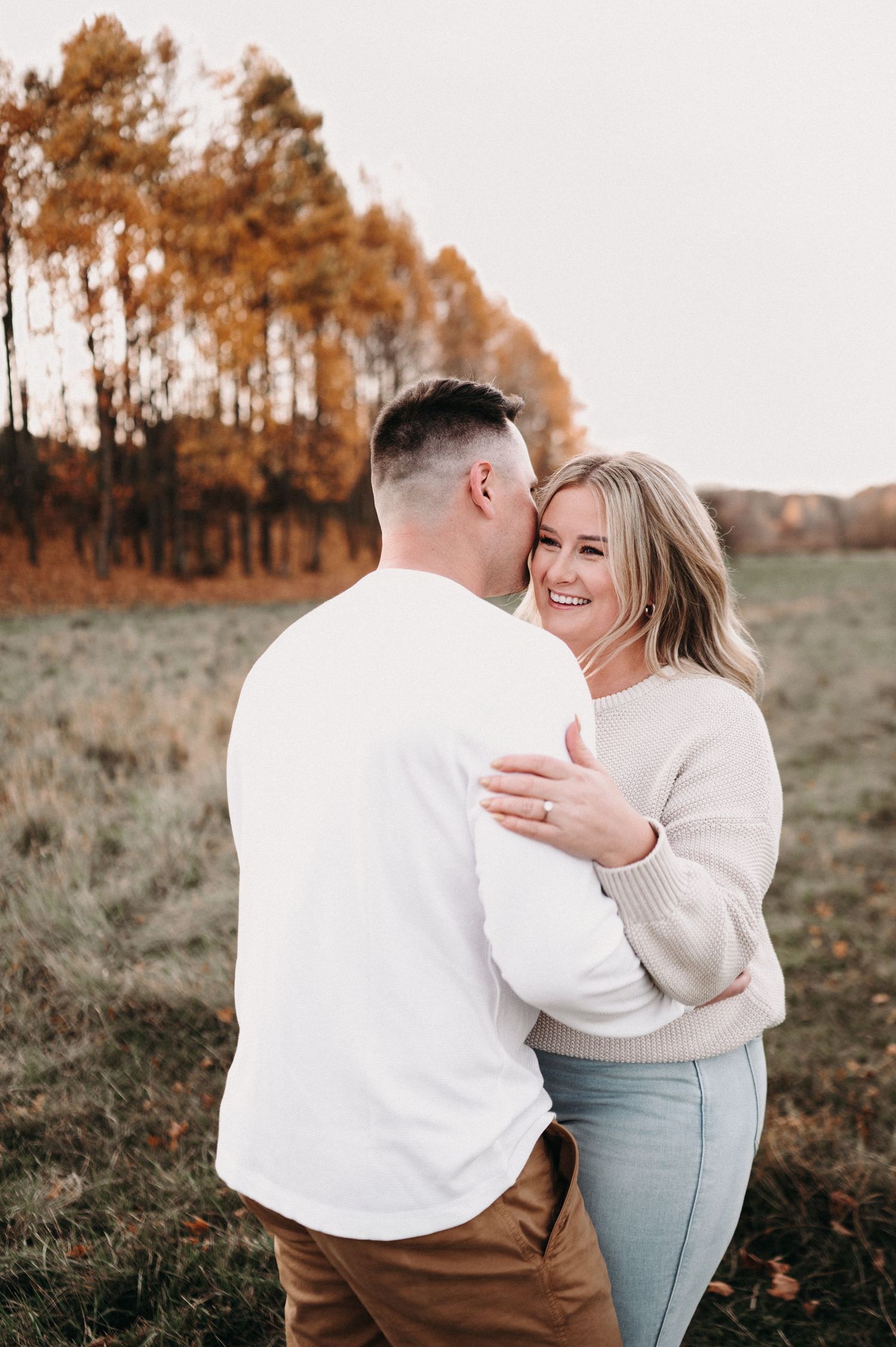 Intimate moment between couple laughing together in autumn field.