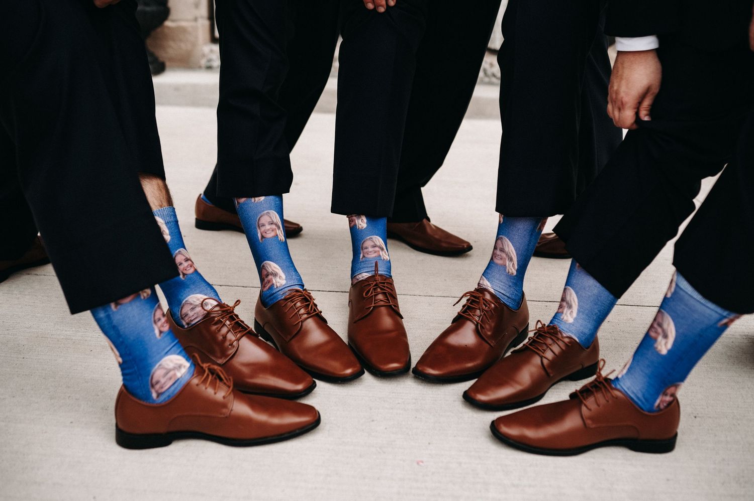 Groomsmen show off matching blue patterned socks with brown leather dress shoes.