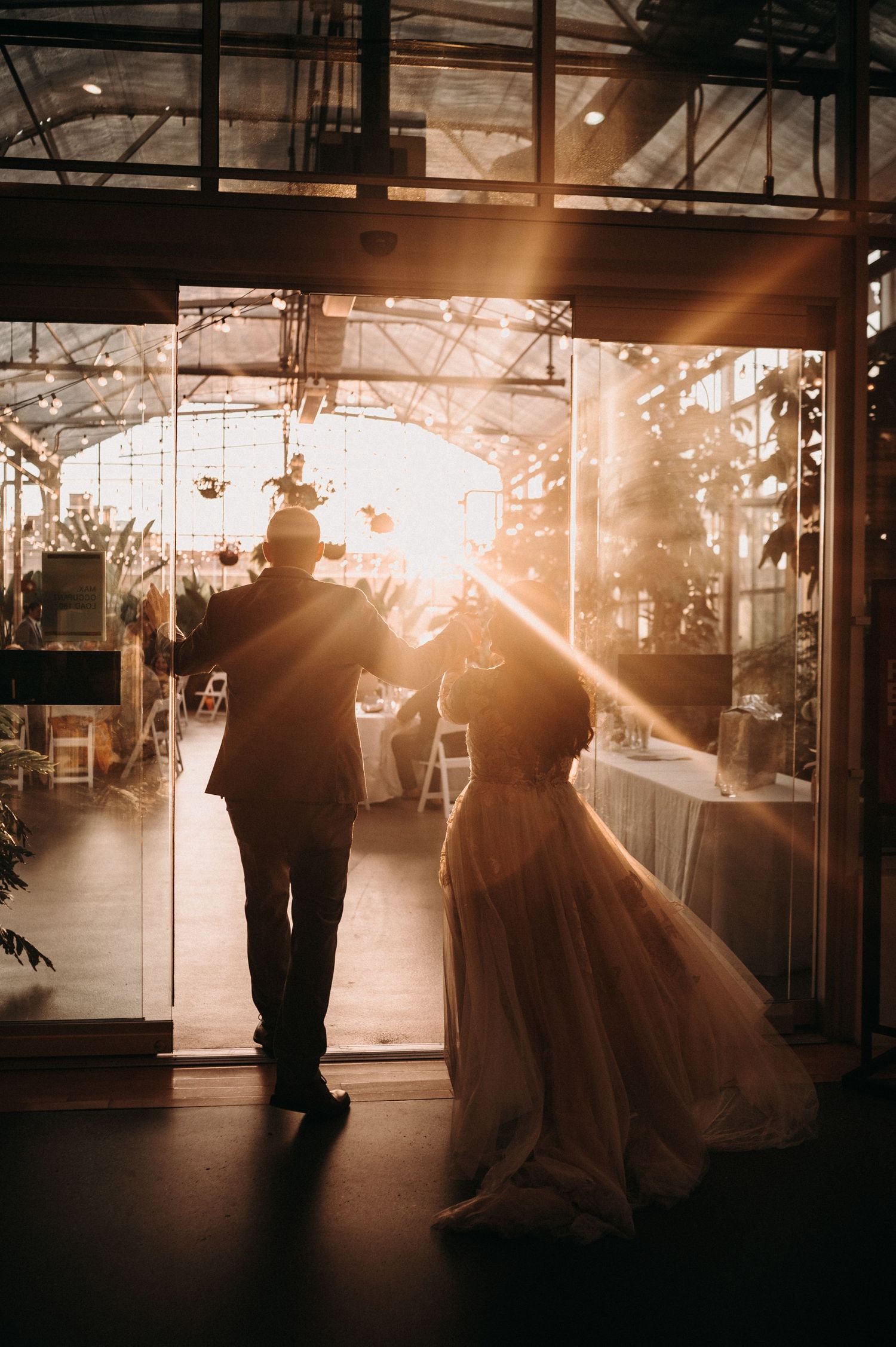 Silhouetted wedding couple standing in doorway with dramatic sunset light streaming through.