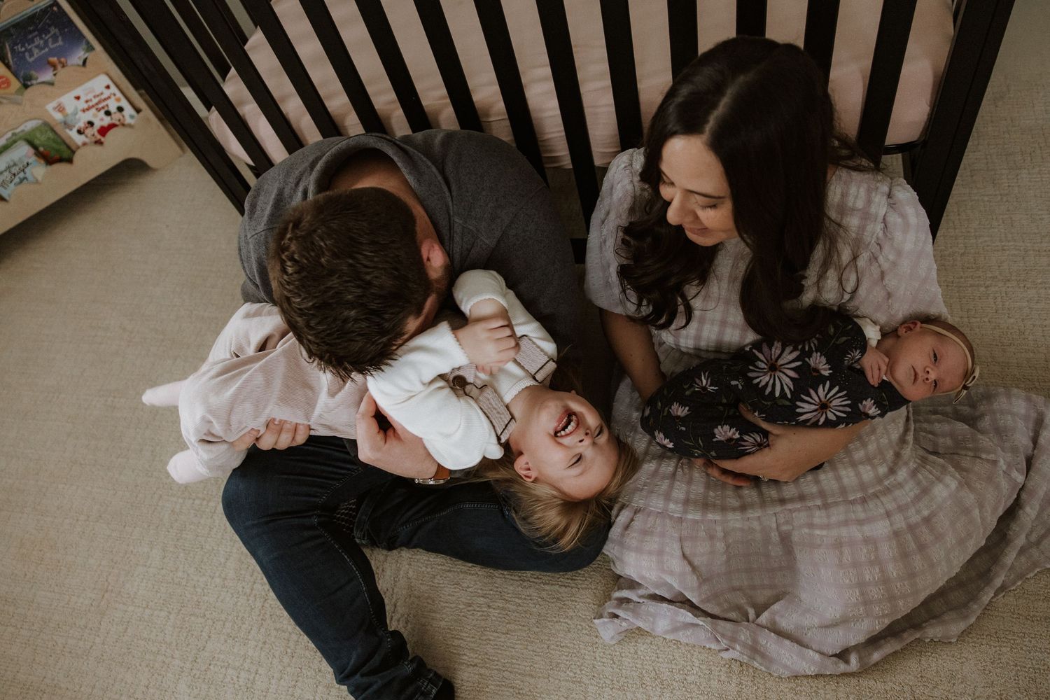 A group of people sit together on the floor in a cozy indoor setting, sharing an intimate moment.