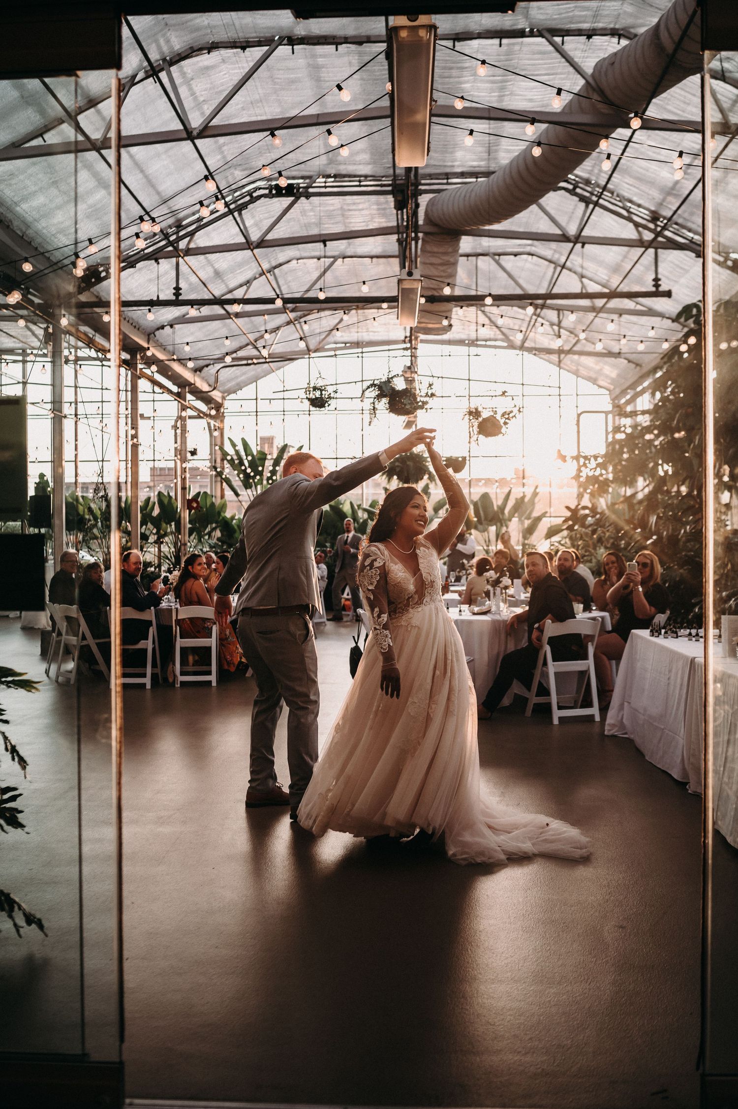 Wedding couple dancing in a greenhouse venue with beautiful natural backlight.