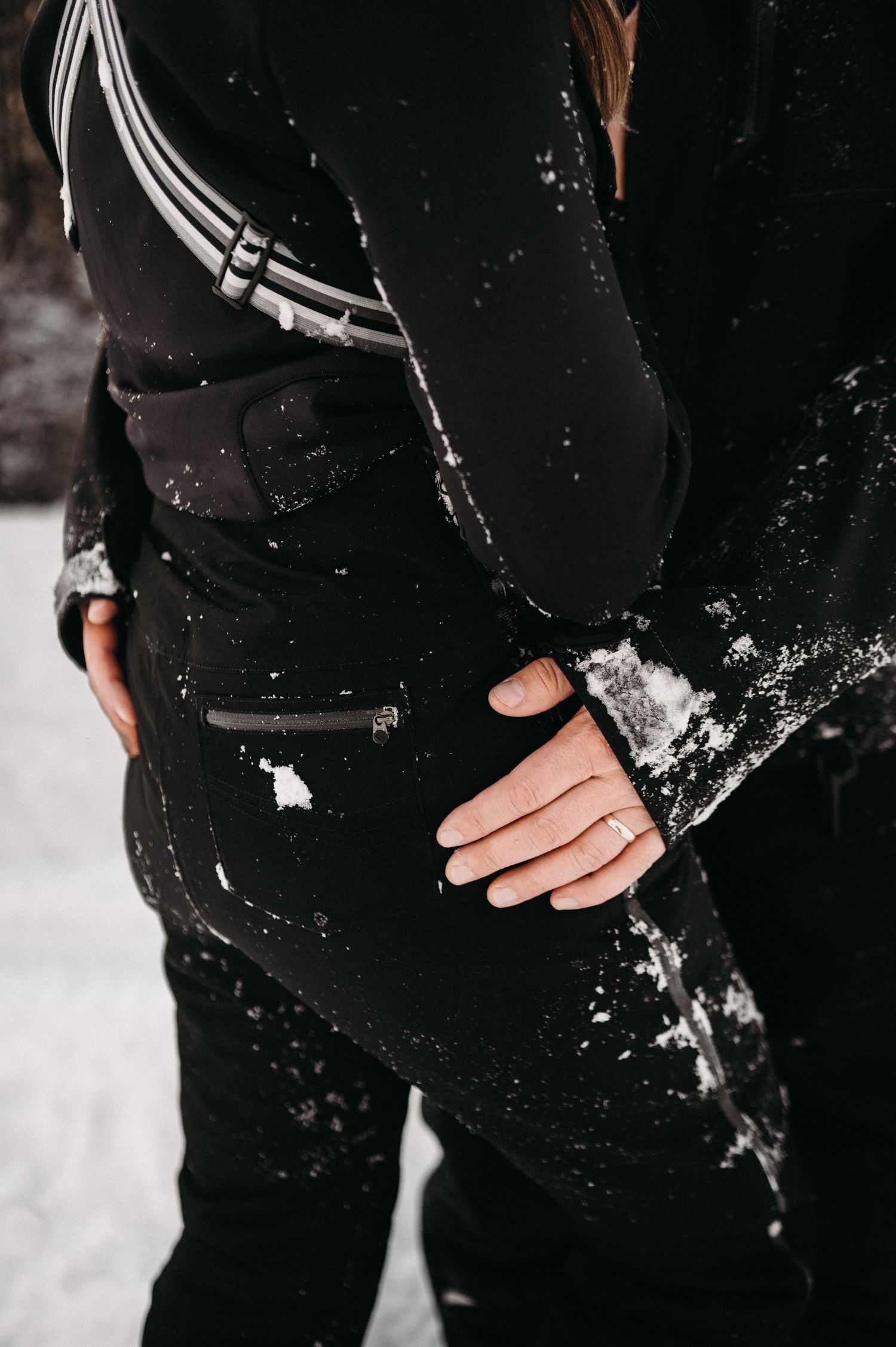Close-up detail of snow-covered black winter clothing with white stripes.