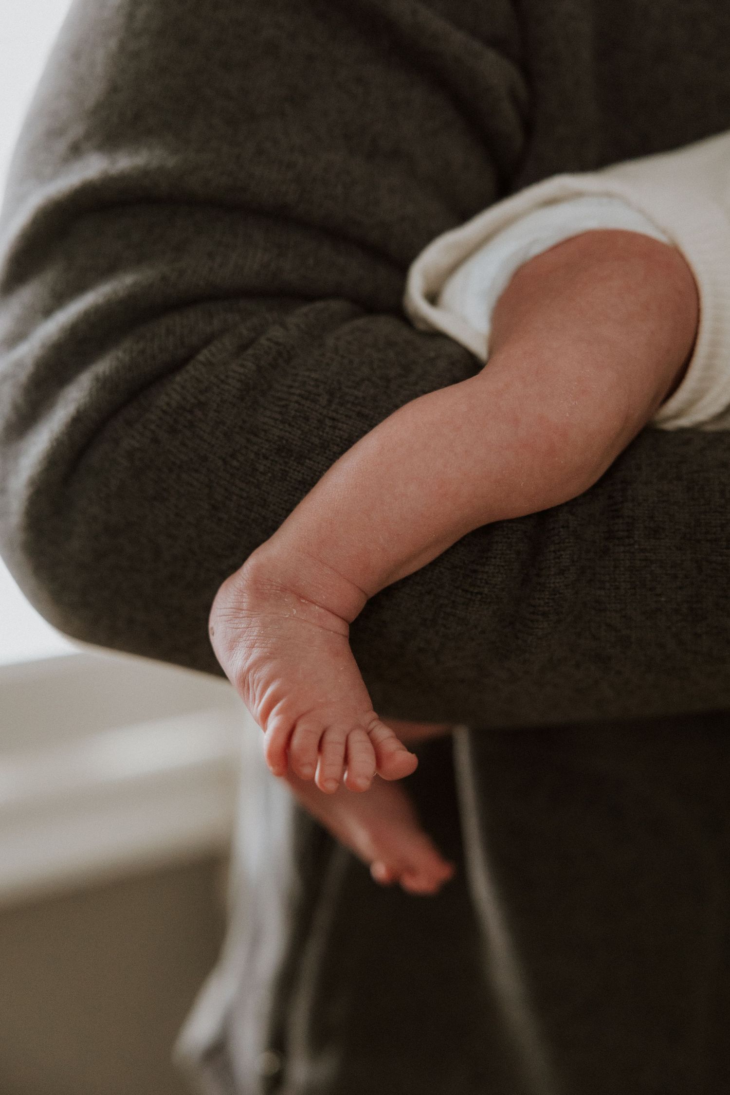 Close-up view of tiny newborn baby feet against dark fabric background.