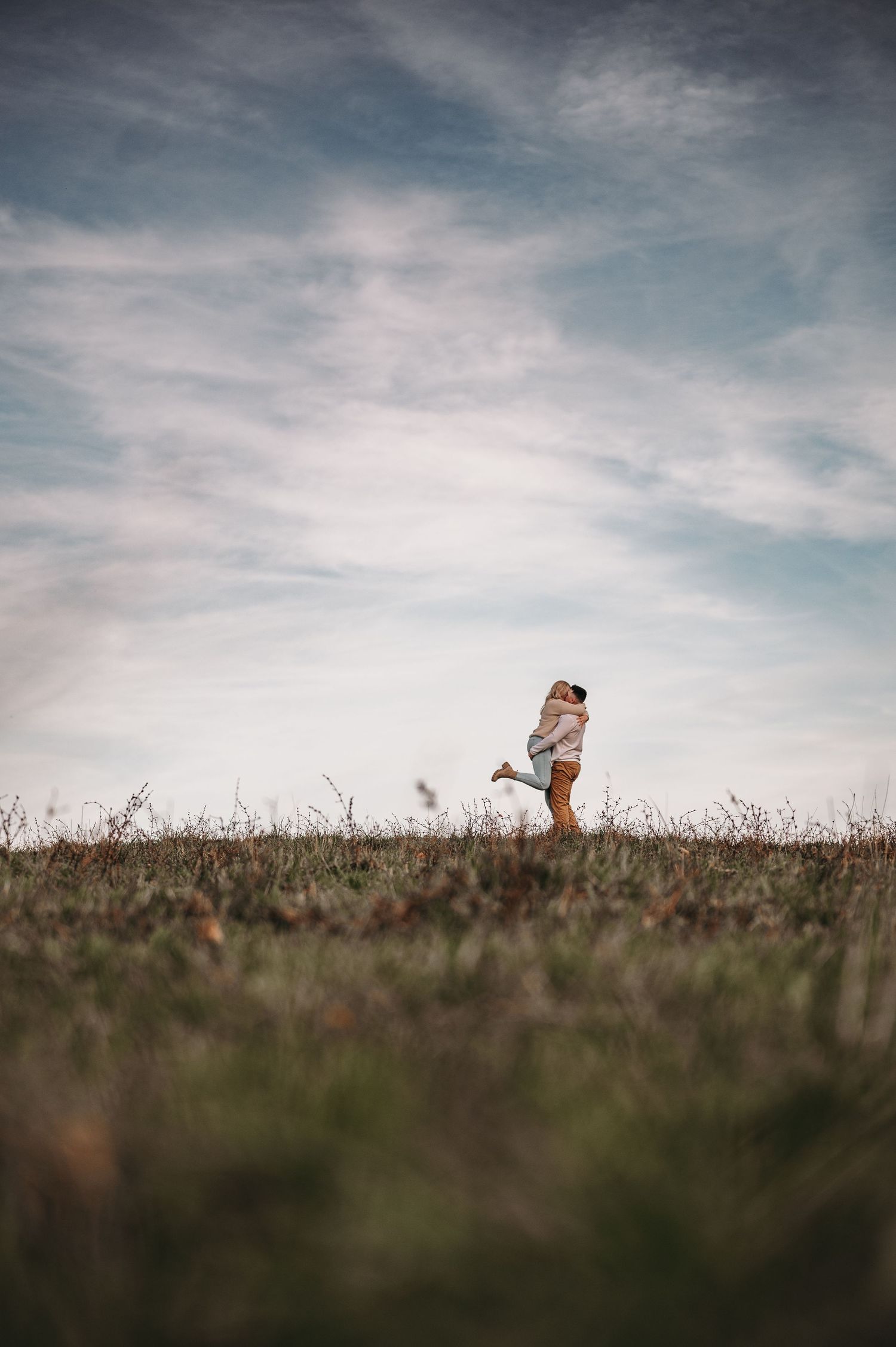 Silhouetted figures in a grassy field under dramatic cloudy sky.